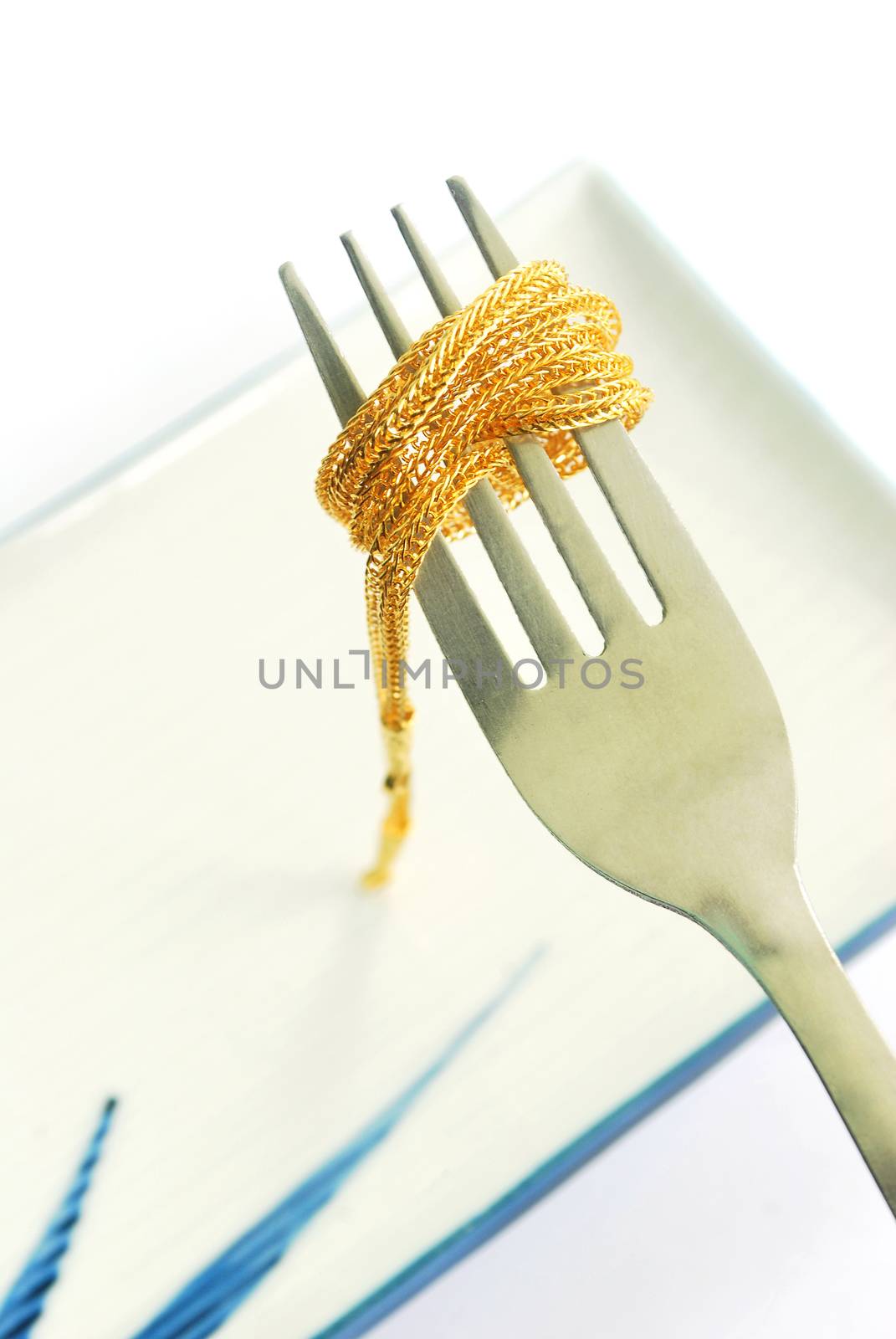 The gold neck weighs about 0.5 grams on the cutlery on white background.