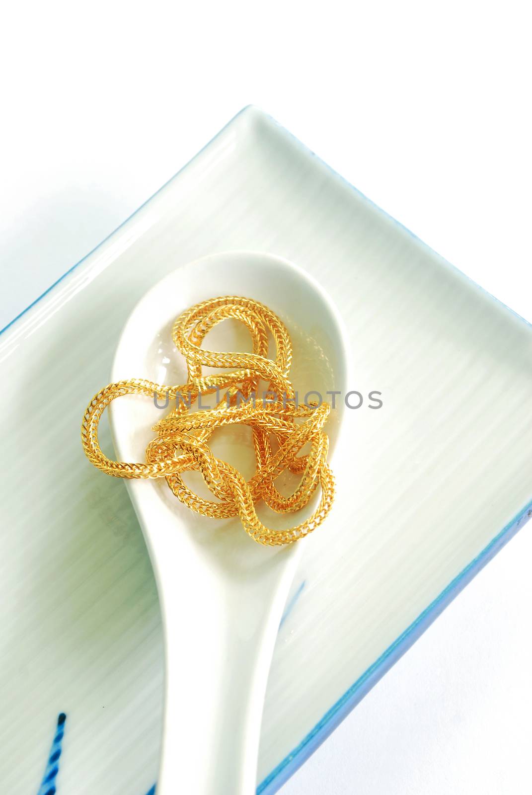 The gold neck weighs about 0.5 grams on a spoon on white background.