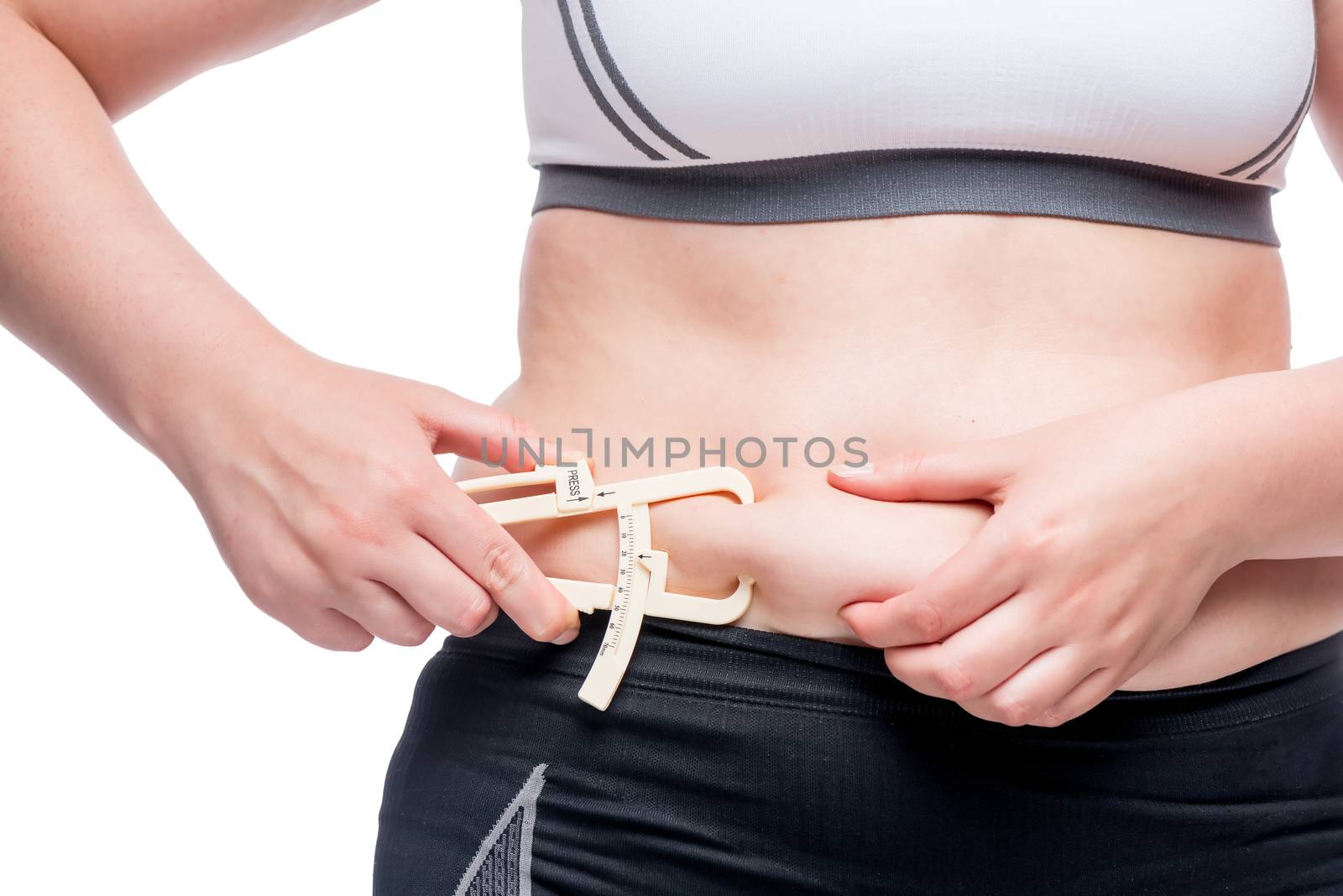 woman measures the level of fat on the abdomen with a tool isolated on white background