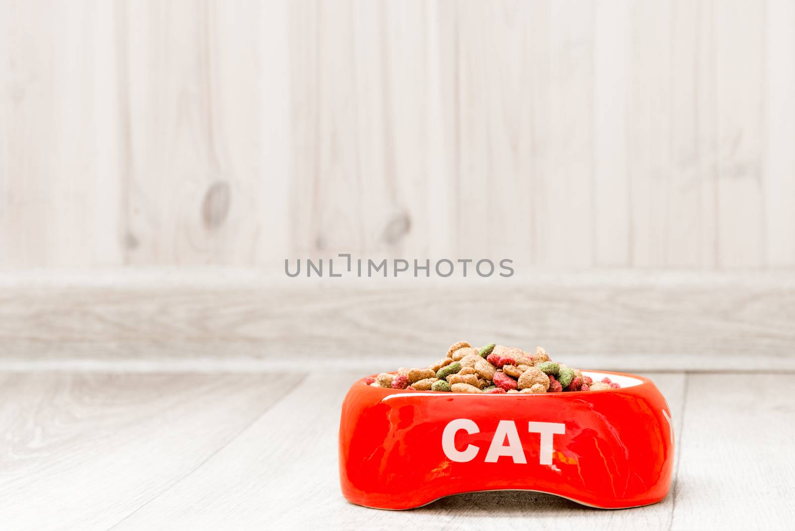 Red bowl for a cat with dry food on the floor in the house close by kosmsos111