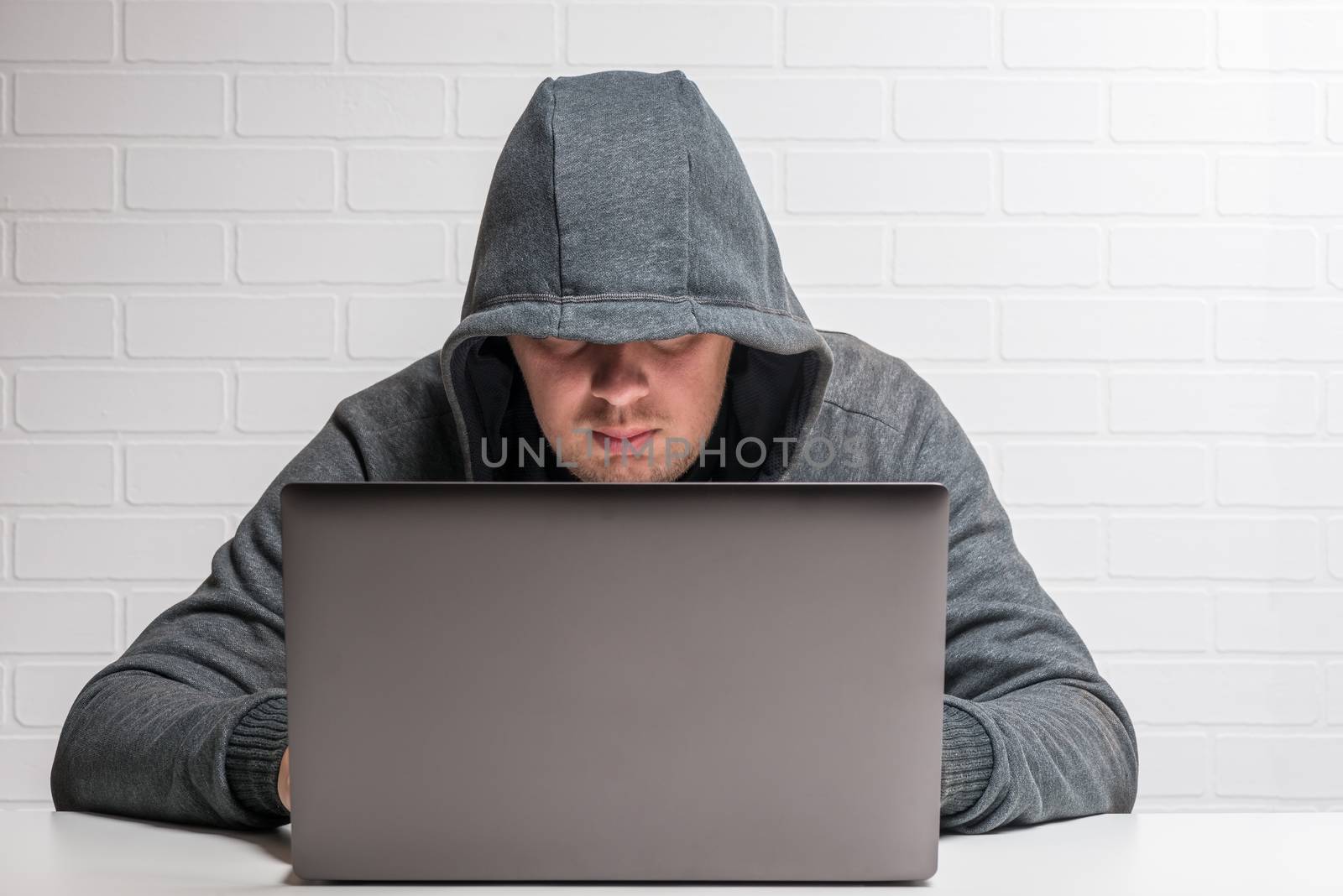 male criminal in the hood hacker spreads the virus to the Internet