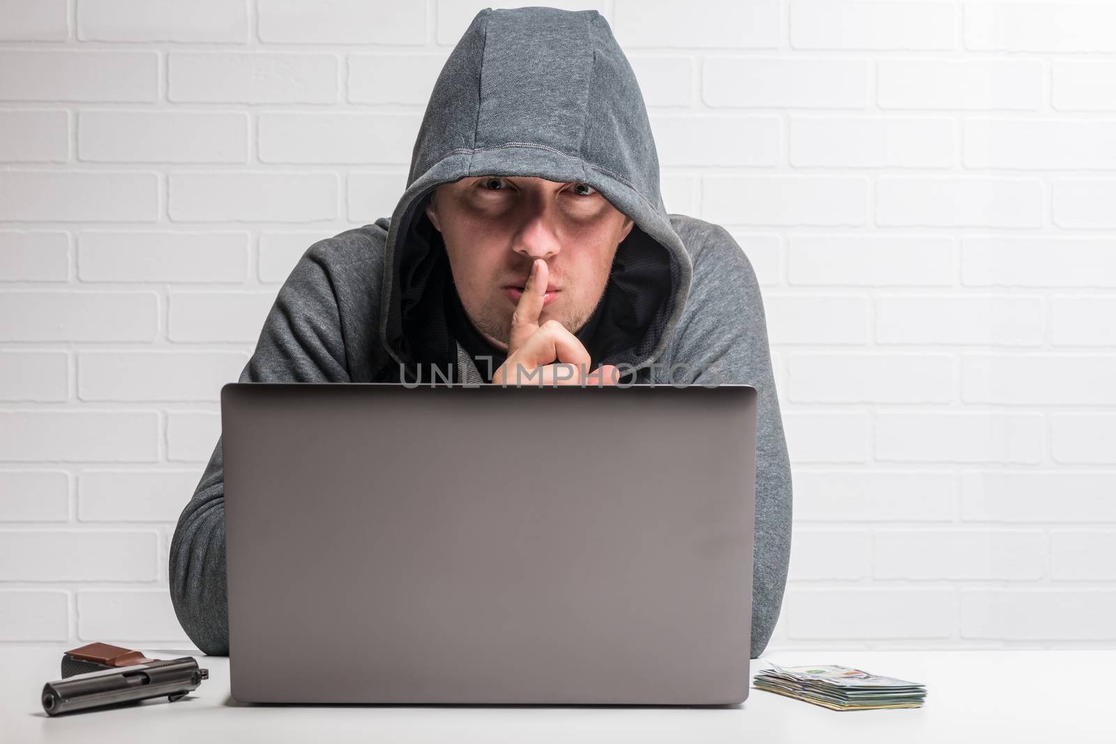 portrait of a criminal hacker with a notebook, weapon and money concept photo