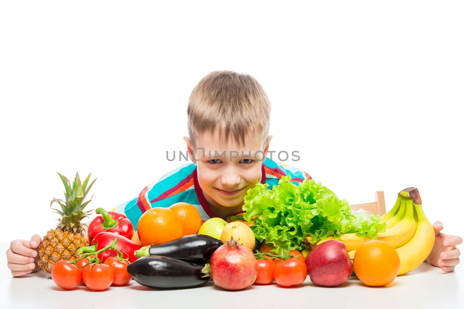 Smiling healthy boy with a bunch of juicy ripe vegetables and fruits on a white background