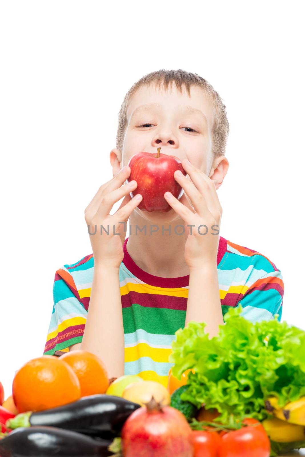 The boy eats a red juicy apple, portrait on a white background