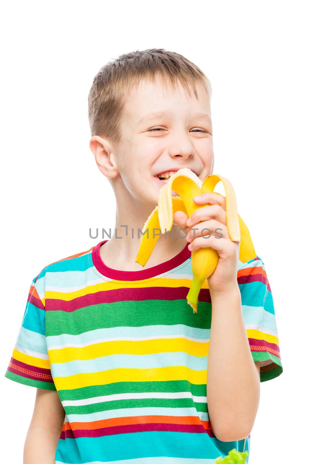 vertical portrait of a boy who eats a tasty banana on a white background, portrait is isolated