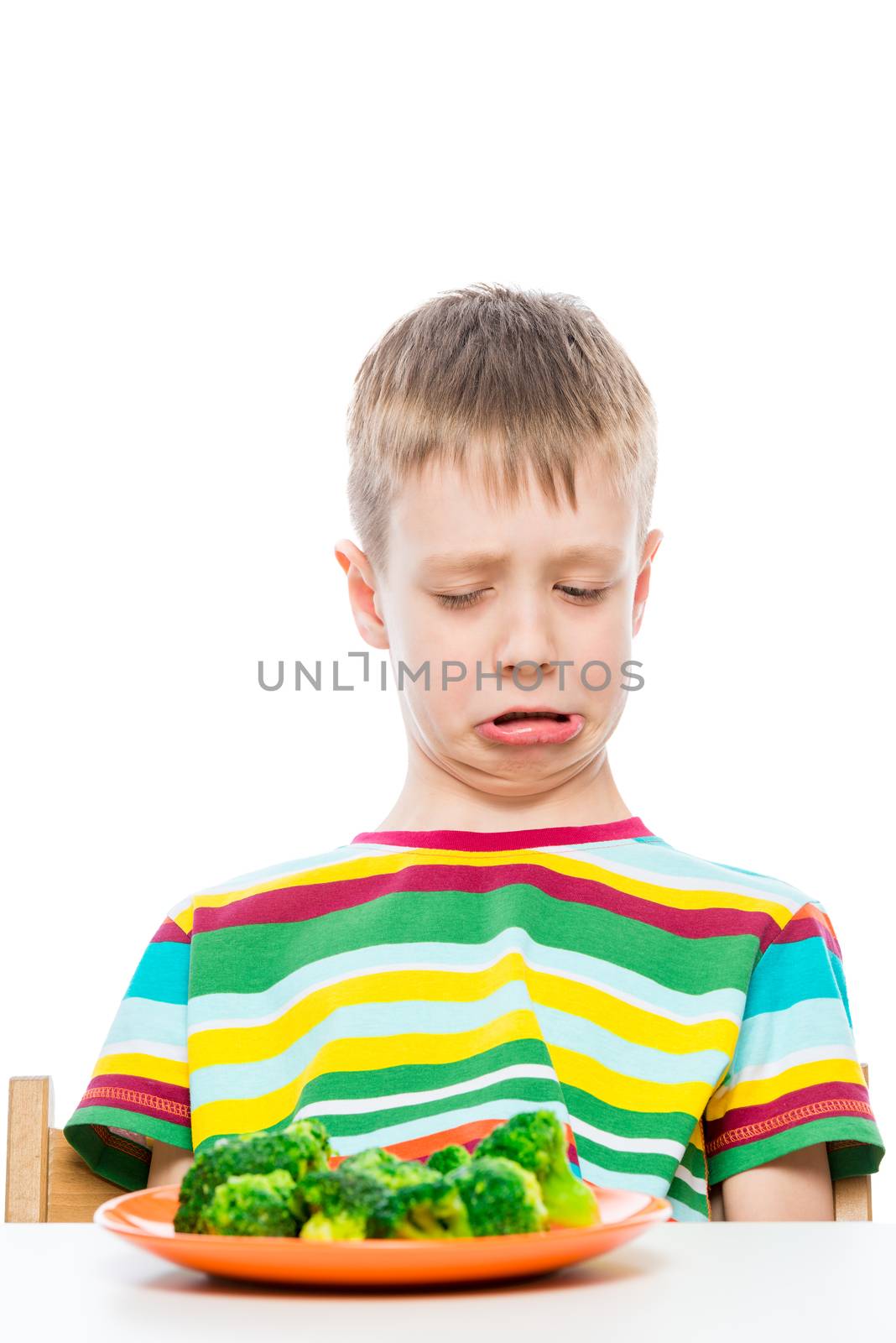 boy with disgust looks at a plate of broccoli, portrait on white background isolated