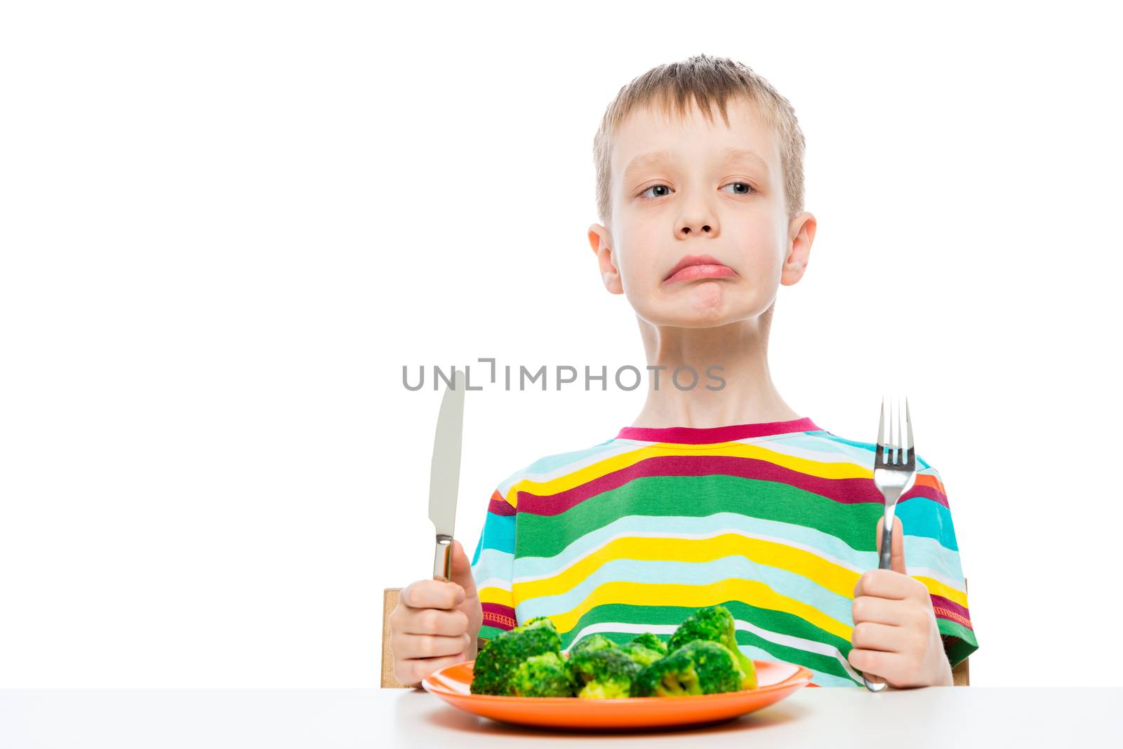 Boy disgusted with eating broccoli, portrait isolated on white background