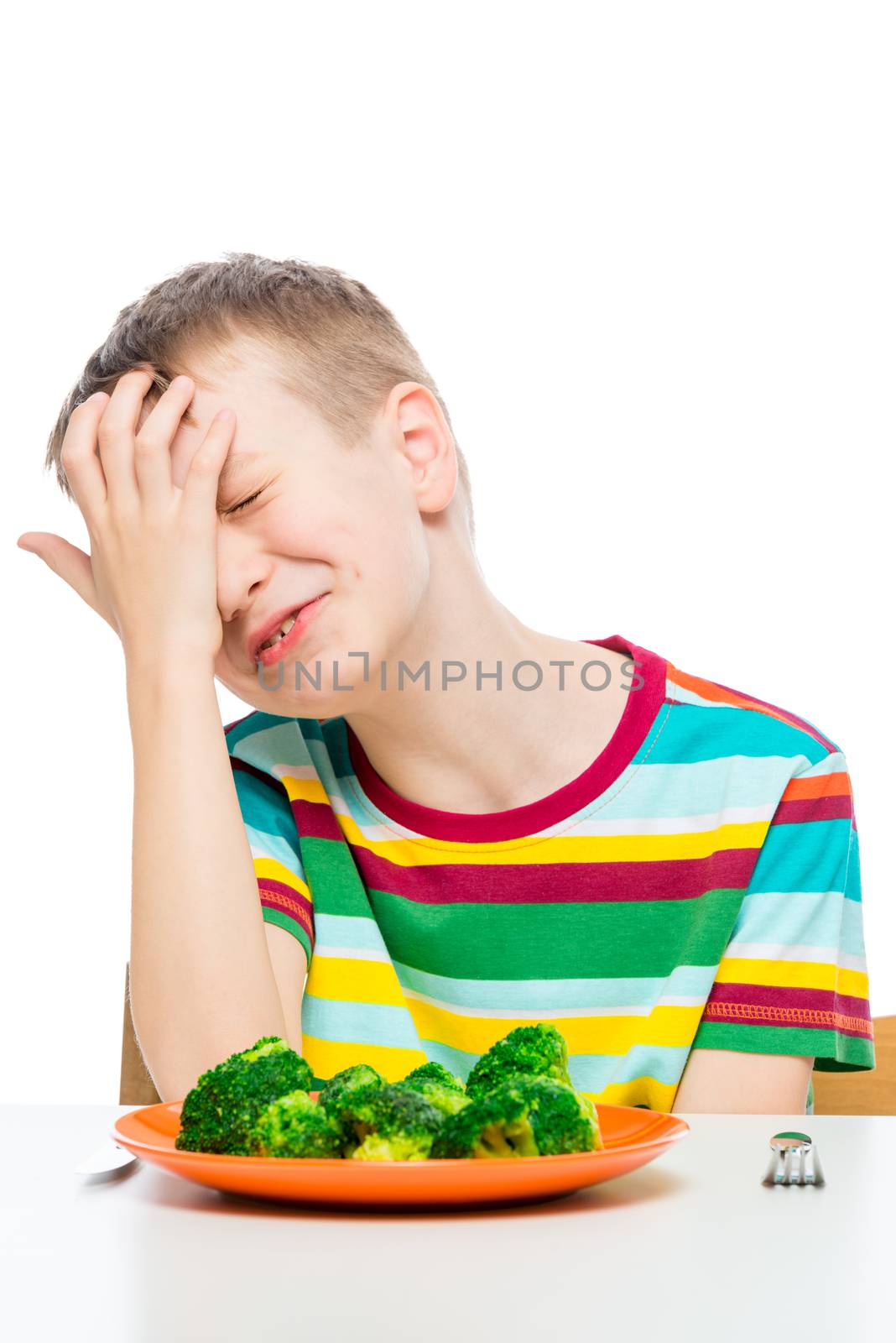 sad boy does not want to eat broccoli, a portrait with a plate on a white background