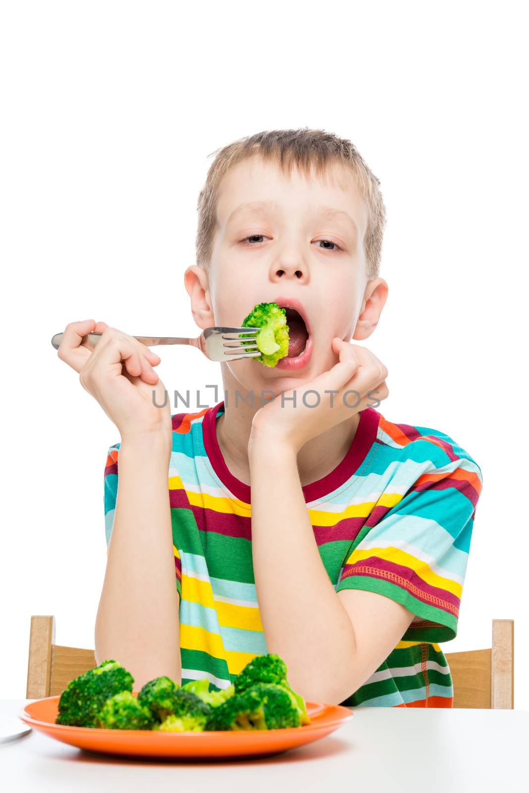 Vertical portrait of a boy who has a diet food, a child eats broccoli on a white background