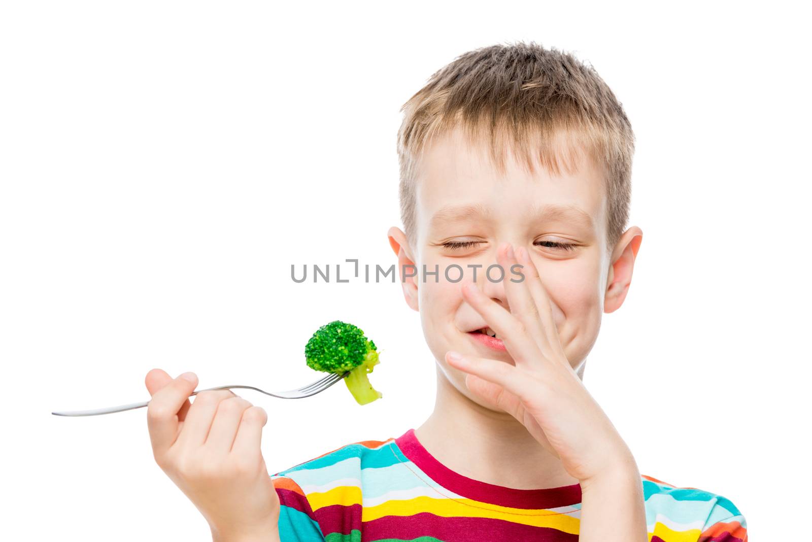 The boy with contempt looks at broccoli, portrait is isolated on white background