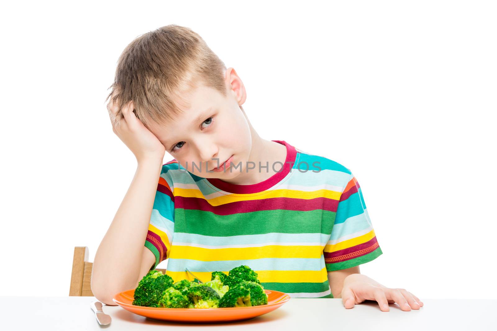 Sad child with a plate of broccoli at the table, portrait isolated