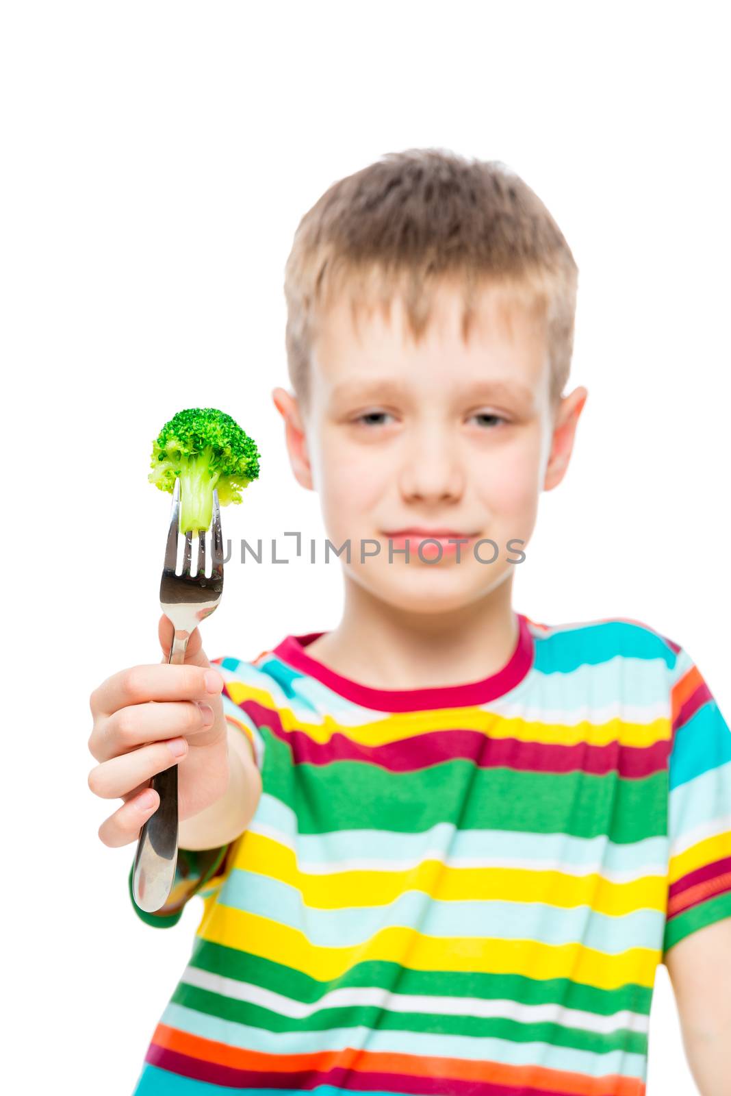 Vertical portrait of a boy with broccoli on a fork, vegetable in focus