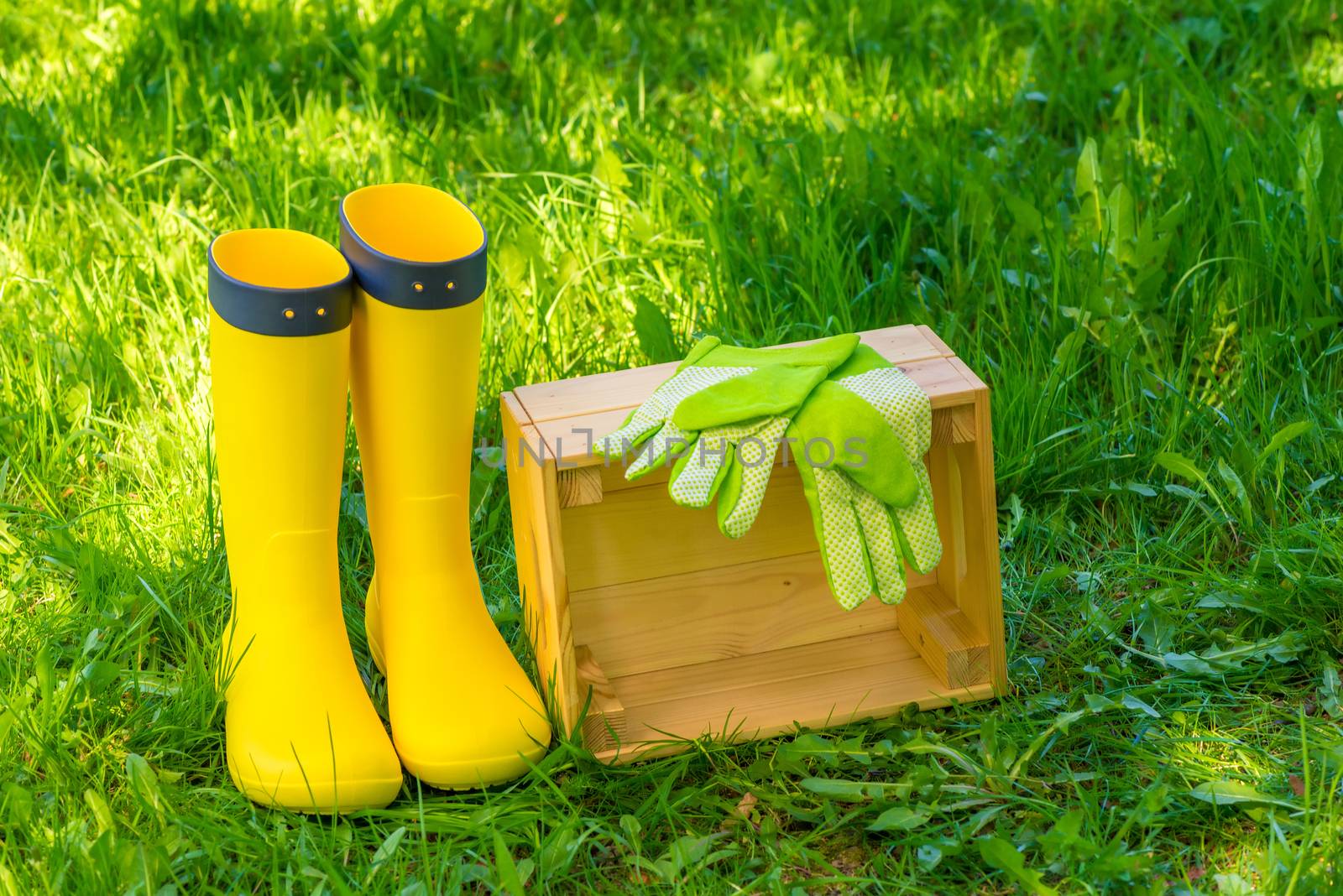 wooden box, green gloves and yellow rubber boots on lush grass i by kosmsos111