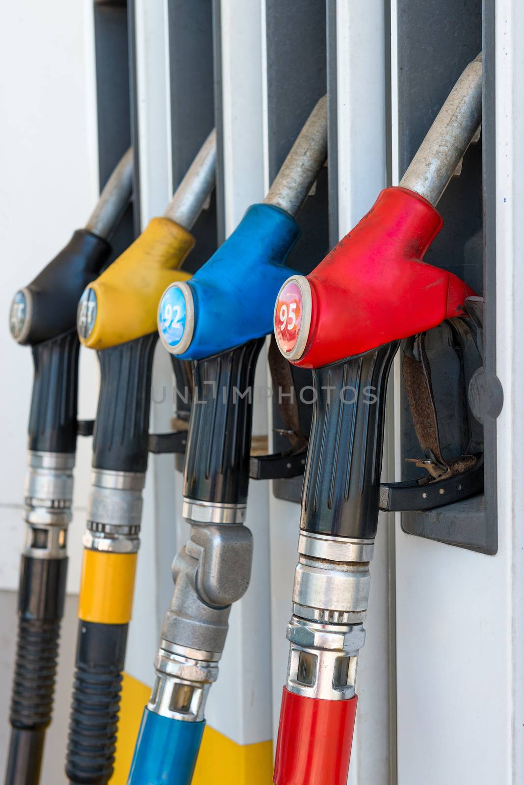 vertical photo of fuel pistols at a gas station close up by kosmsos111