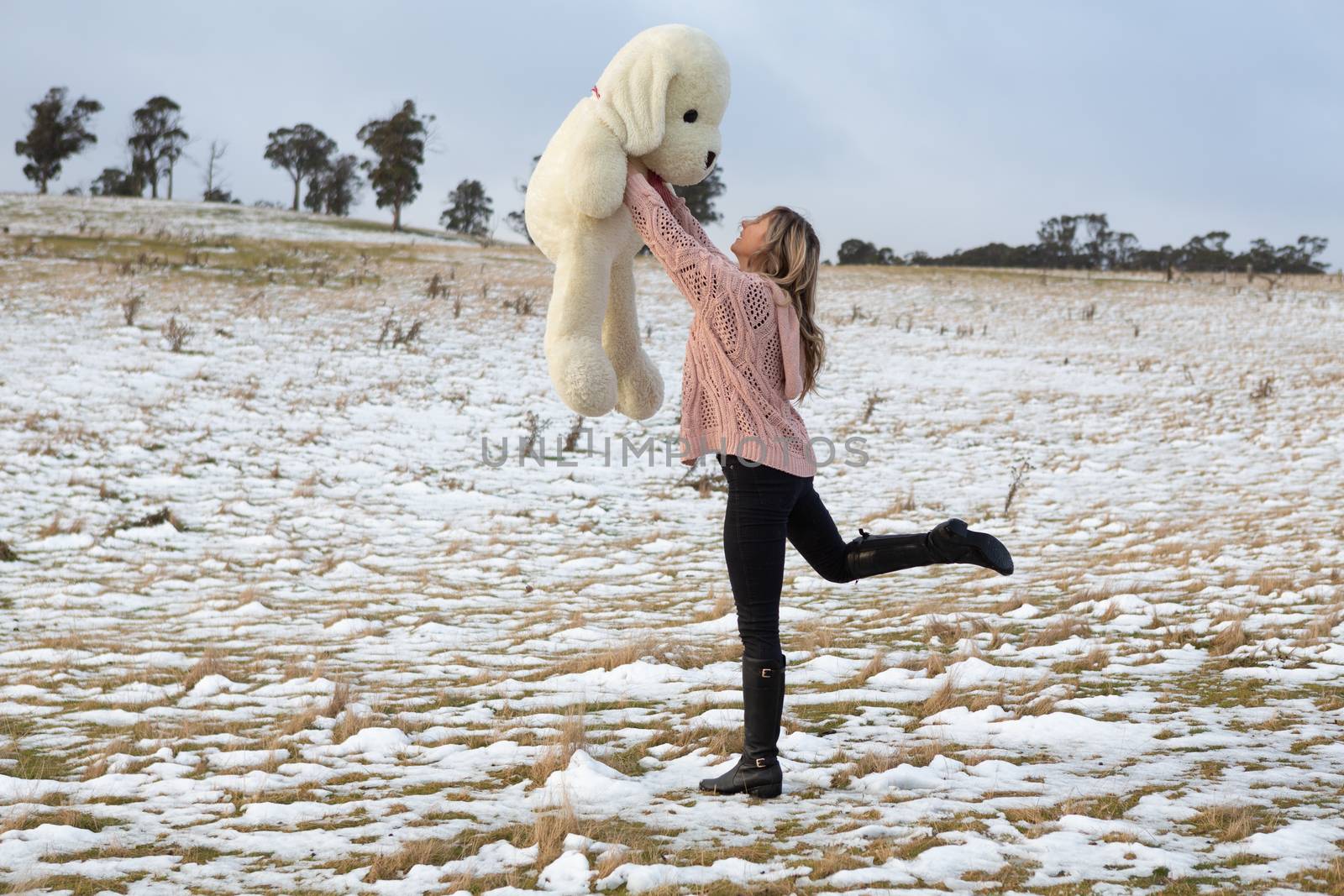 Woman frolicking in the snow with teddy bear by lovleah