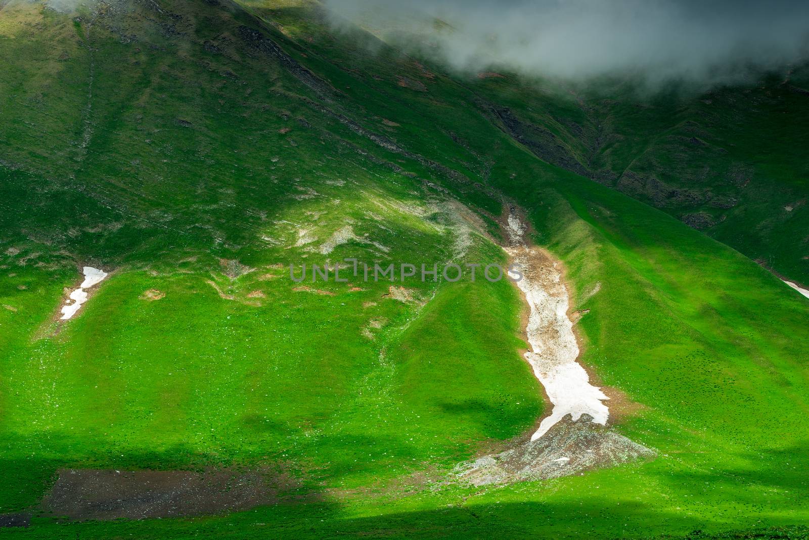 Green mountainside with remnants of snow after winter, Caucasus in June