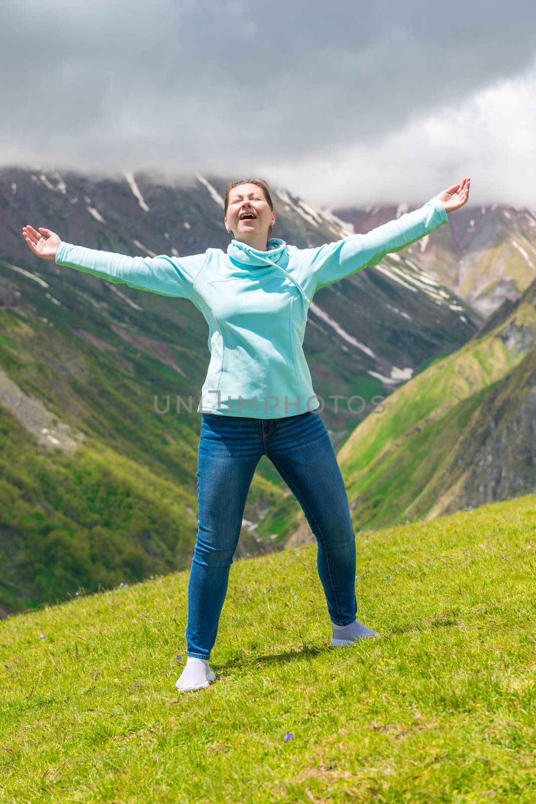 Emotional woman with open arms in the mountains enjoys freedom