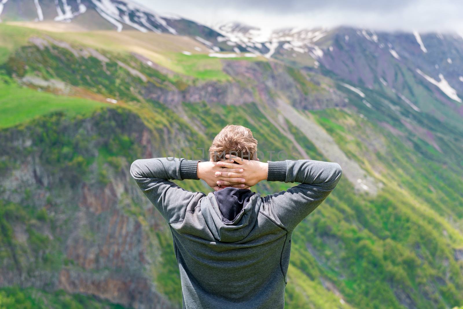 View from the back A man admires the beautiful scenery in the Caucasus Mountains