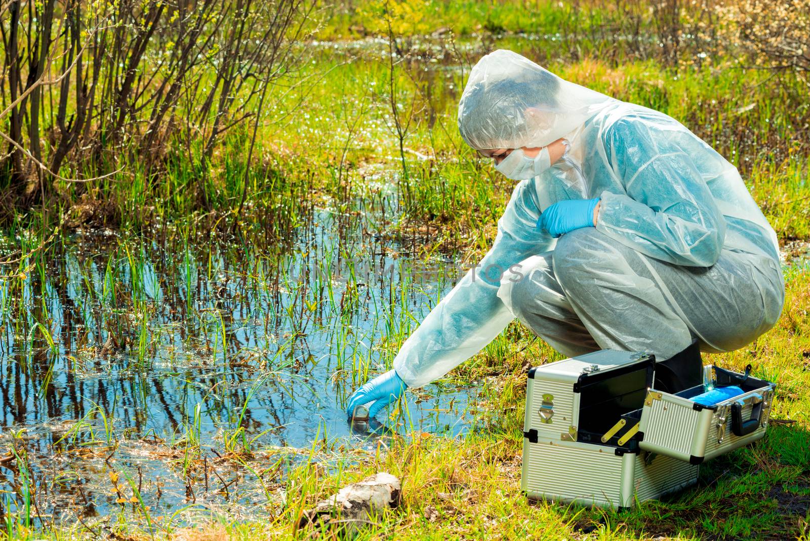 experienced ecologist on the shore of a forest lake takes water samples