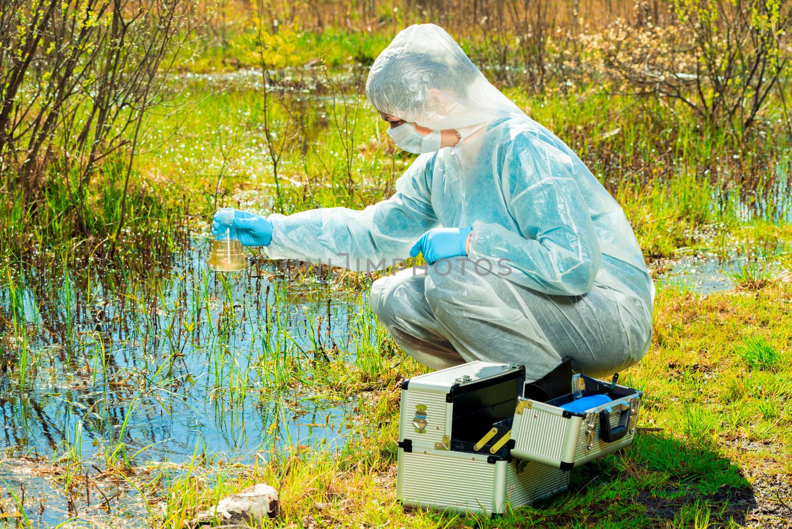 environmentalist on the shore of a forest lake takes water samples after an environmental disaster