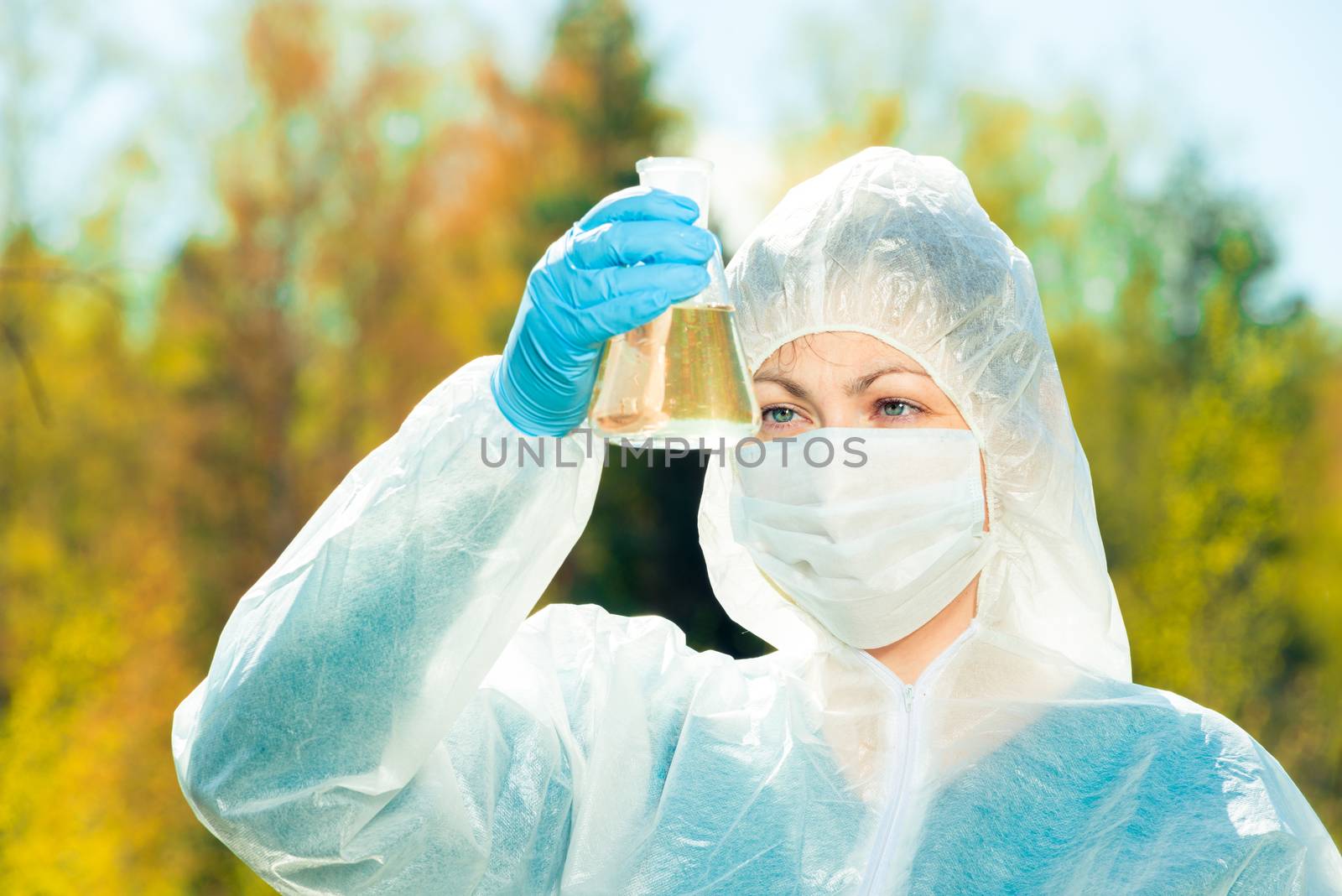closeup portrait of an environmental chemist with a flask of water from a forest lake
