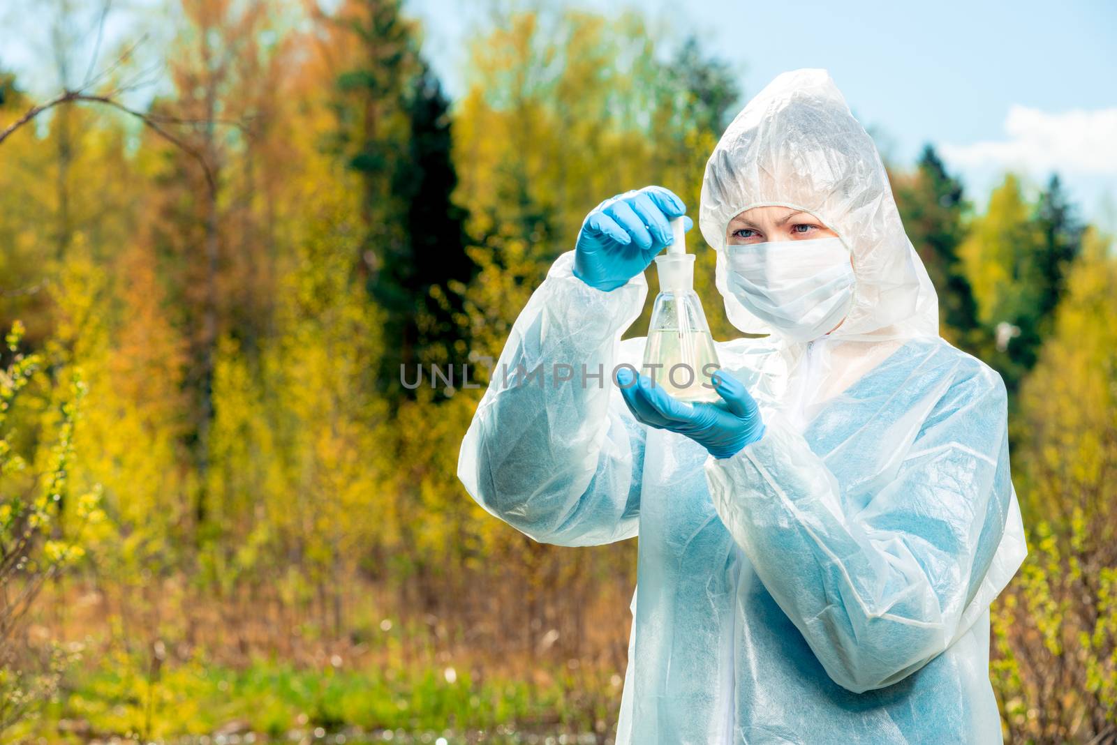 a scientist studies the composition of water from a forest lake in nature