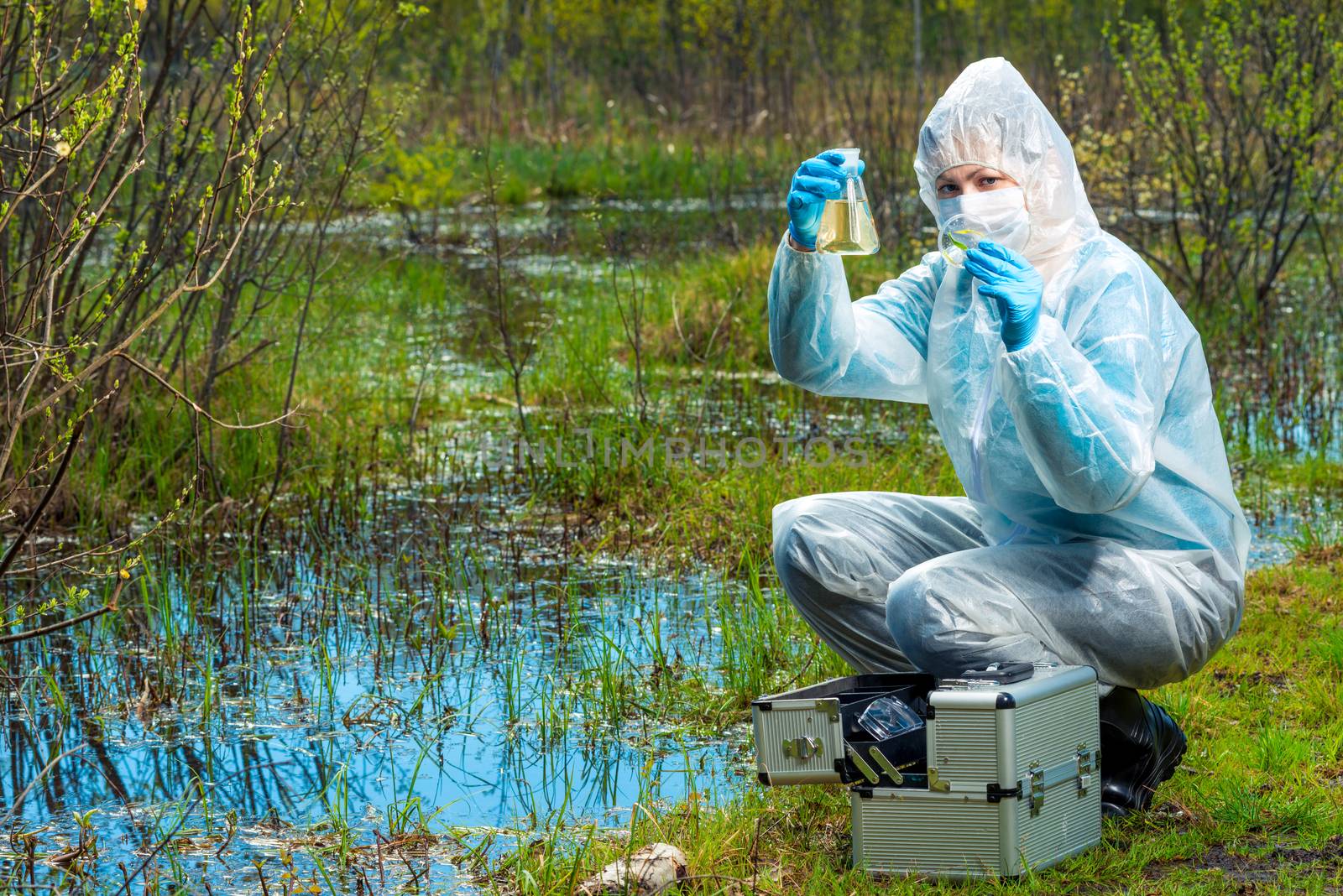 a female ecologist with samples of water and flora from a lake i by kosmsos111