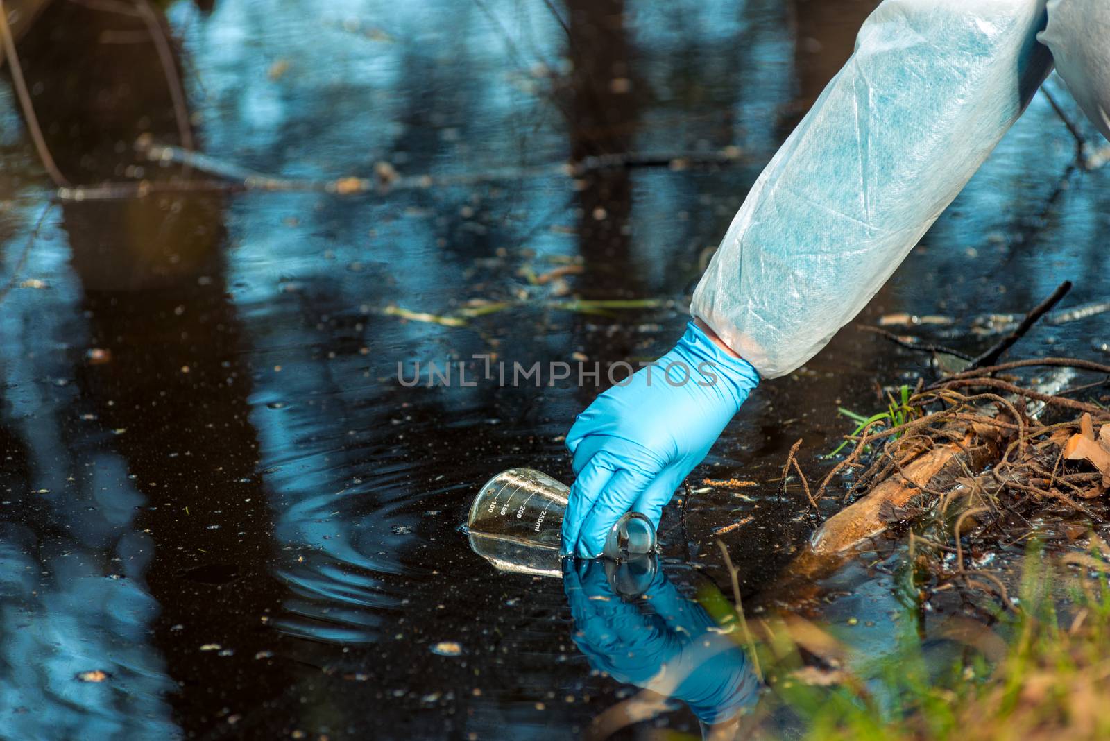 close-up environmentalist hand of a researcher, produces a process of taking a sample of water from a river