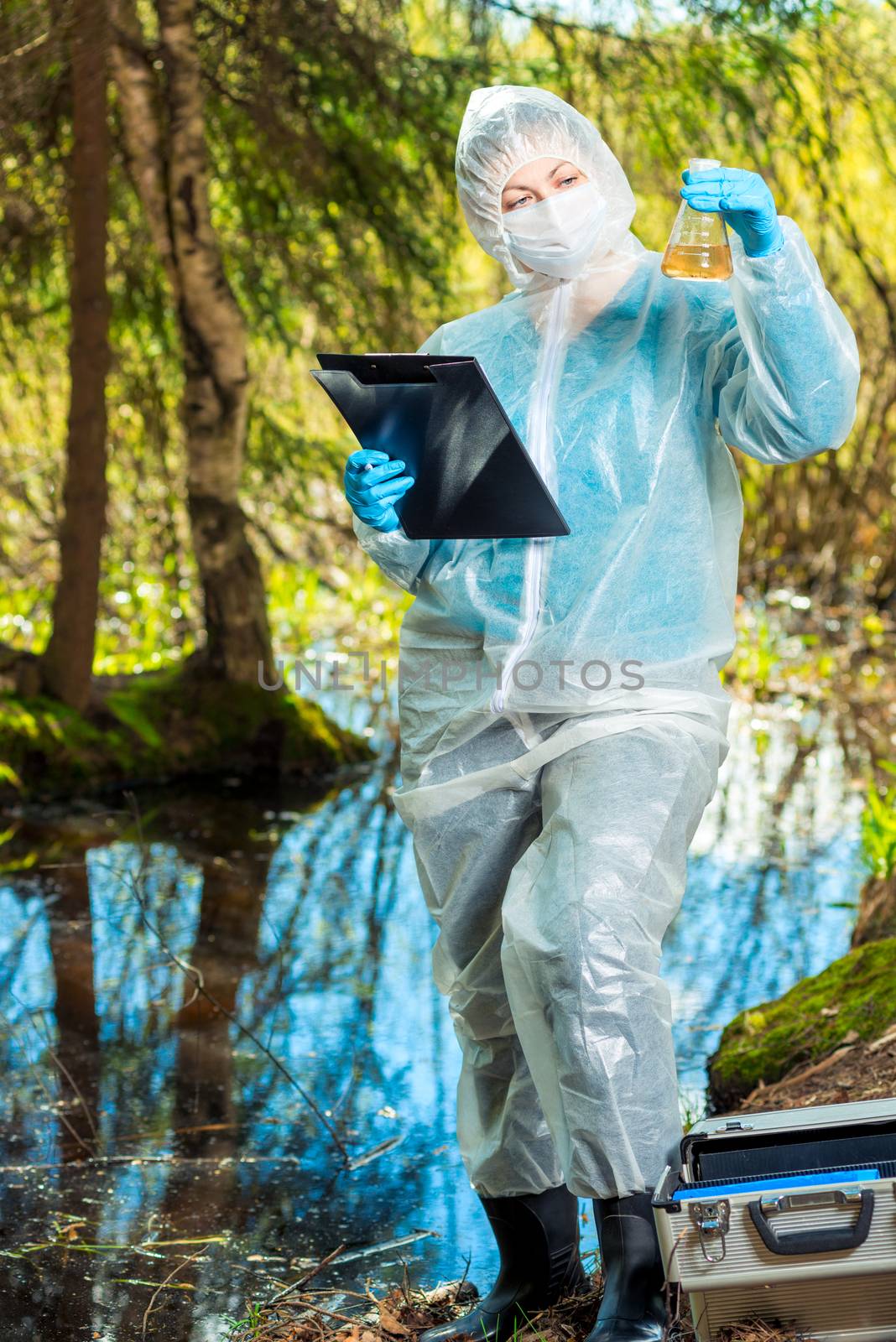 a female ecologist analyzes the state of water in a forest river by kosmsos111