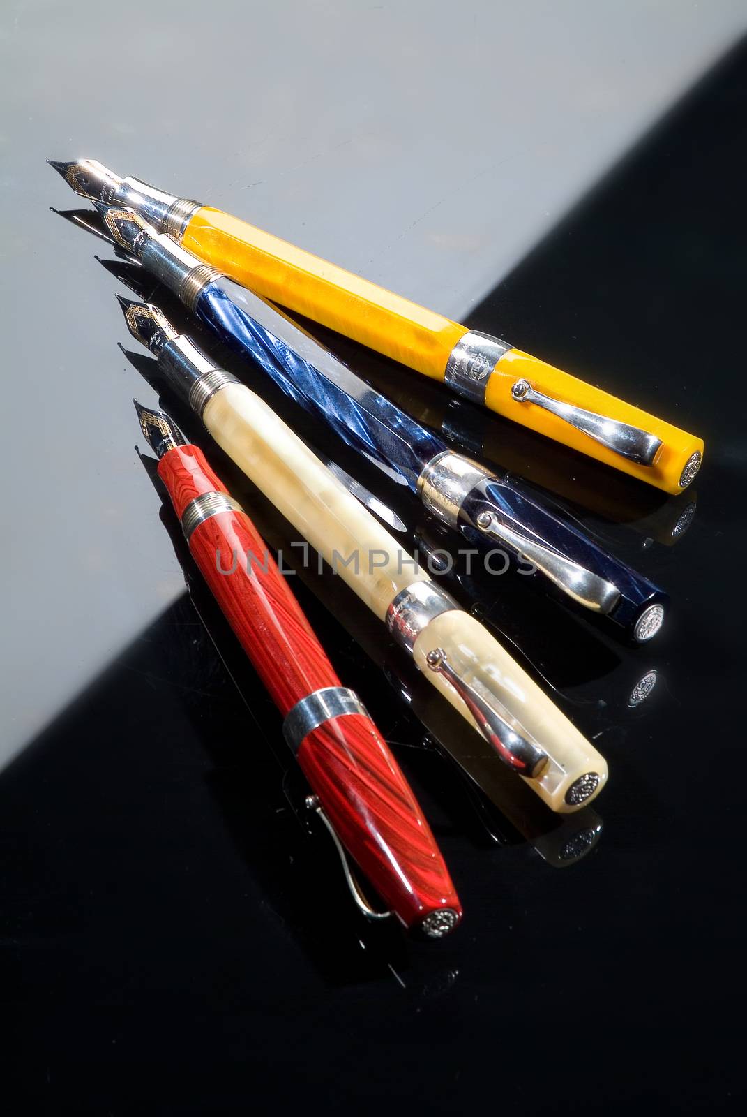 Four different pens on a glass background with highlight