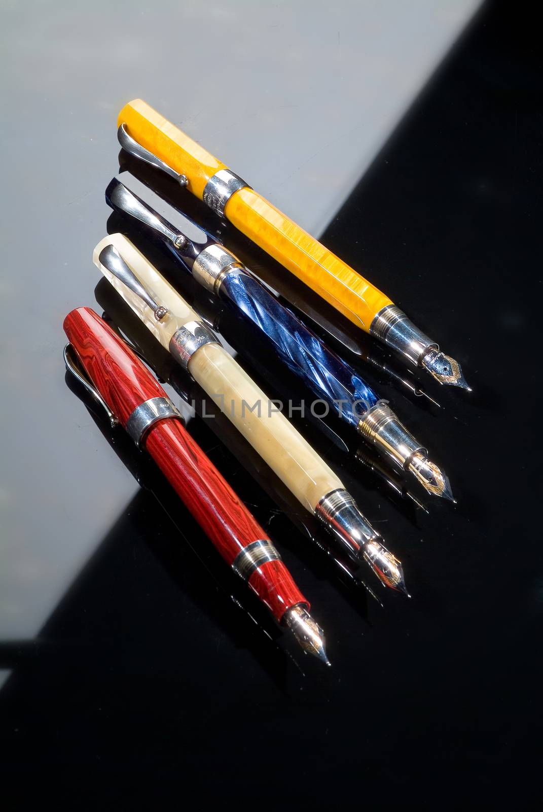 Four different pens on a glass background with highlight