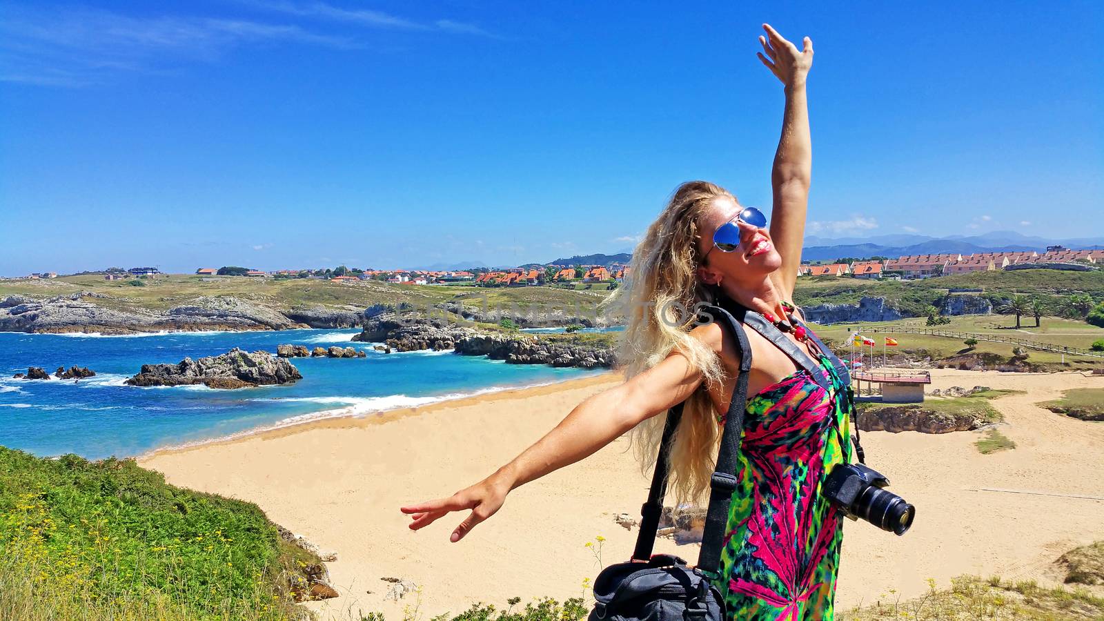 Blonde girl in sunglasses with camera, against sand beach in sunny day by zakob337