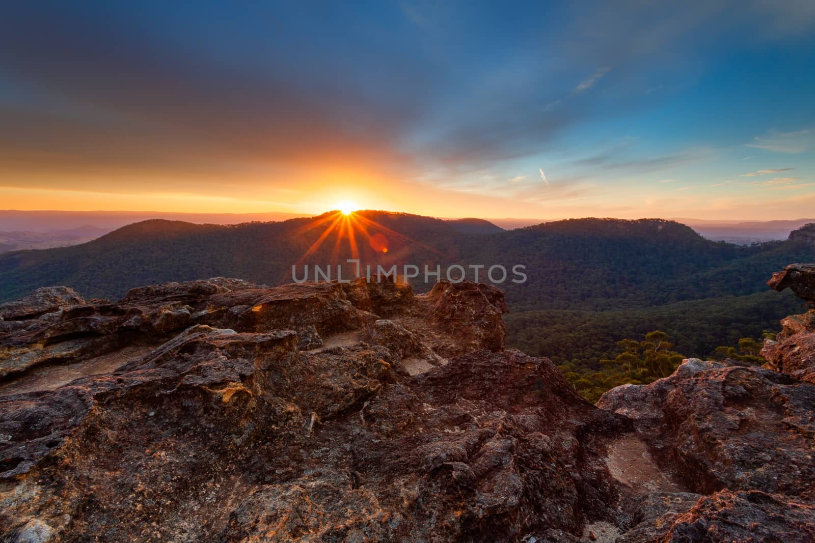 Sunburst as the sunset behind the Blue Mountains ranges lighting up the sky and clouds with warm  hues