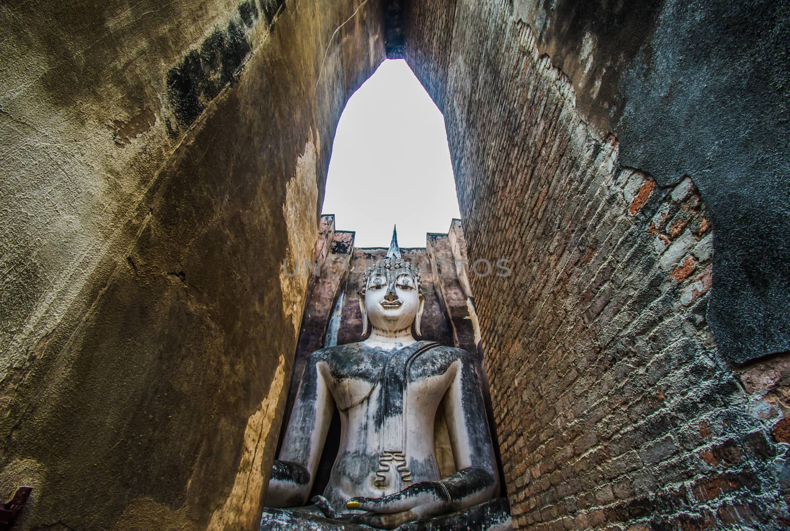 Sukhothai Historical Park, Thailand, traveller with ancient Buddha statue at Wat Si Chum temple. by anuraksir