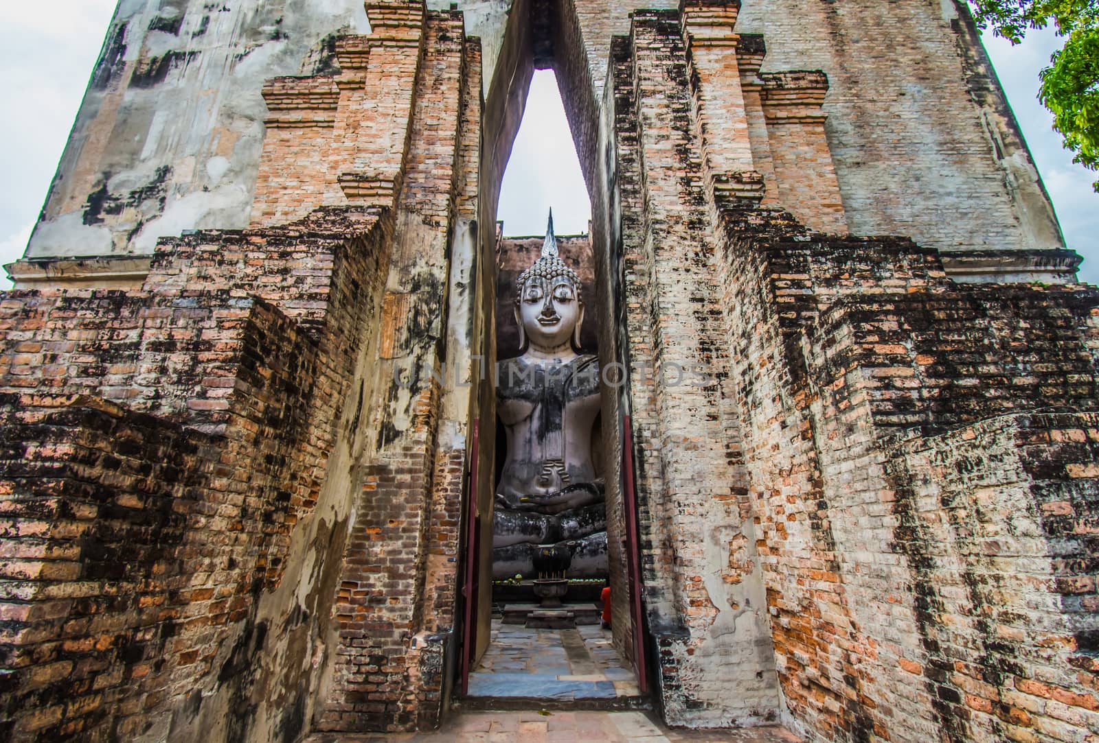 Sukhothai Historical Park, Thailand, traveller with ancient Buddha statue at Wat Si Chum temple. by anuraksir