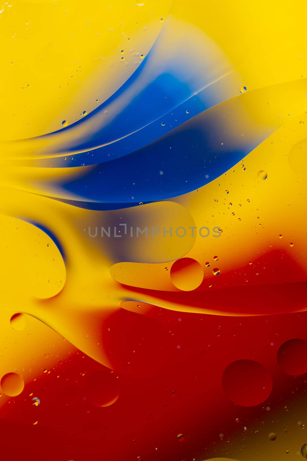 Abstract oil spots in motion on water on blurred yellow backgrou by alexsdriver