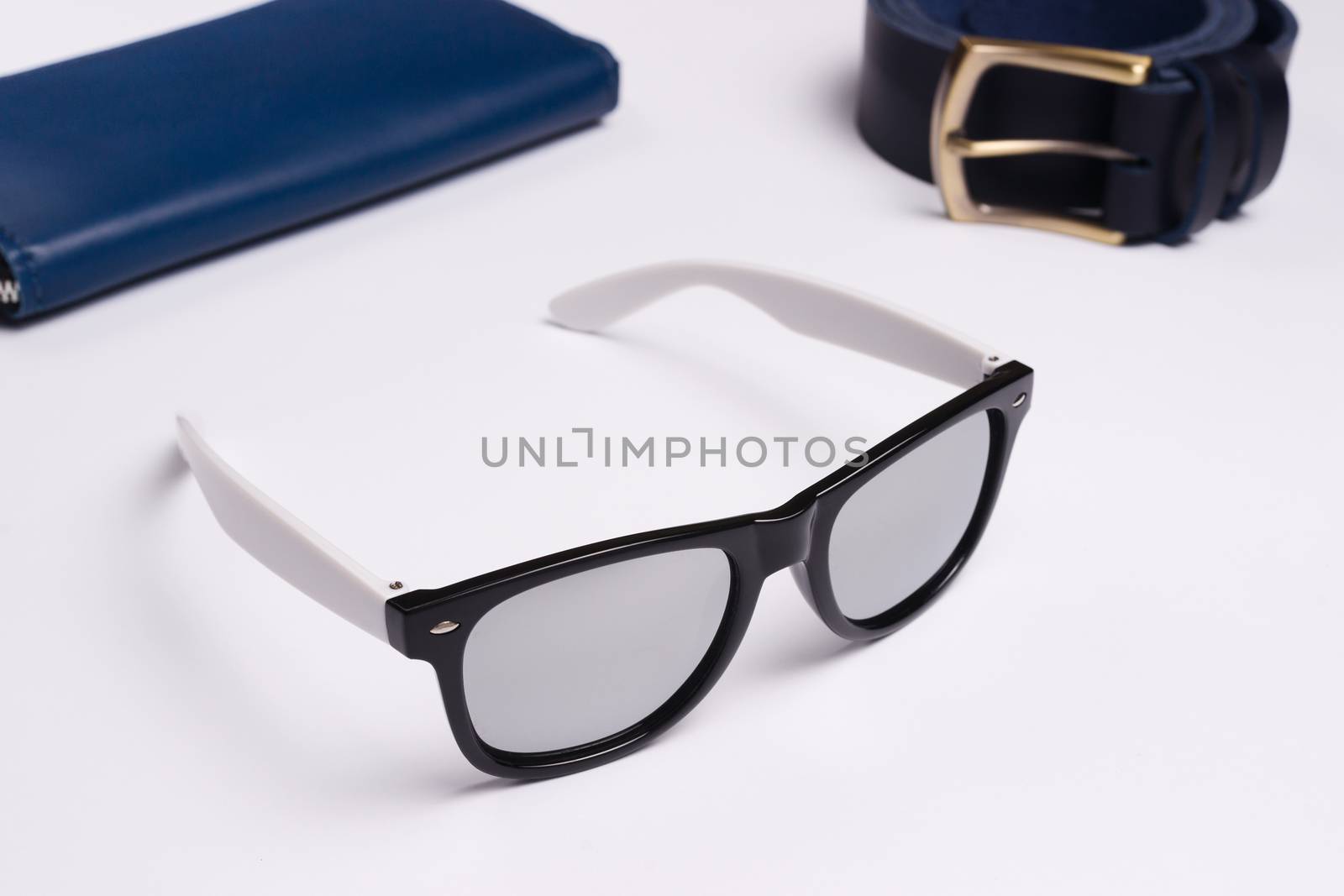 Mirror sunglasses on white background closeup. Leather wallet and belt behind a sunglasses. Stock photo of fashion accessories.