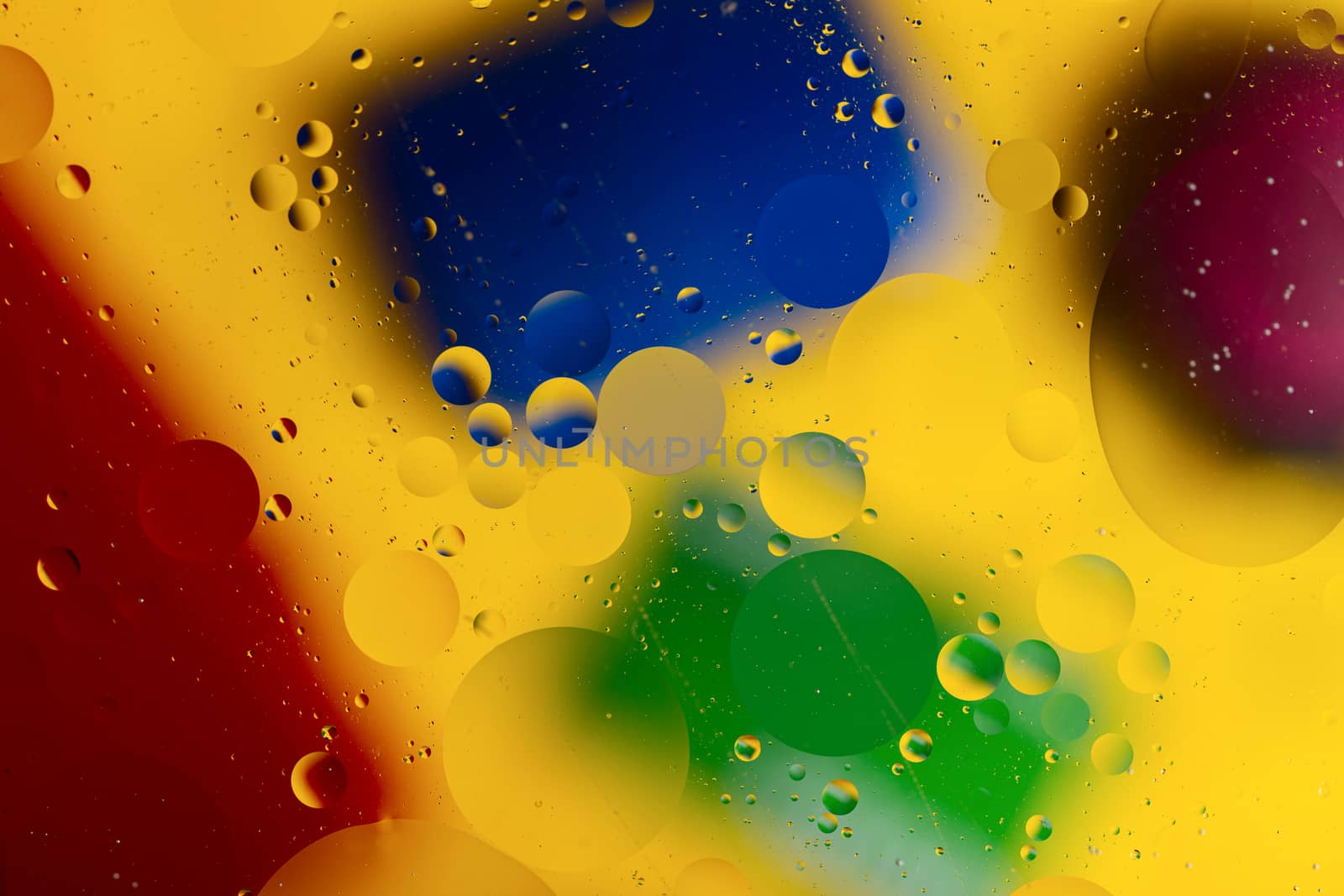 Abstract oil spots in motion on water on blurred yellow background. Red, green, purplee and blue spots on blurred background. Photo with small depth of field.