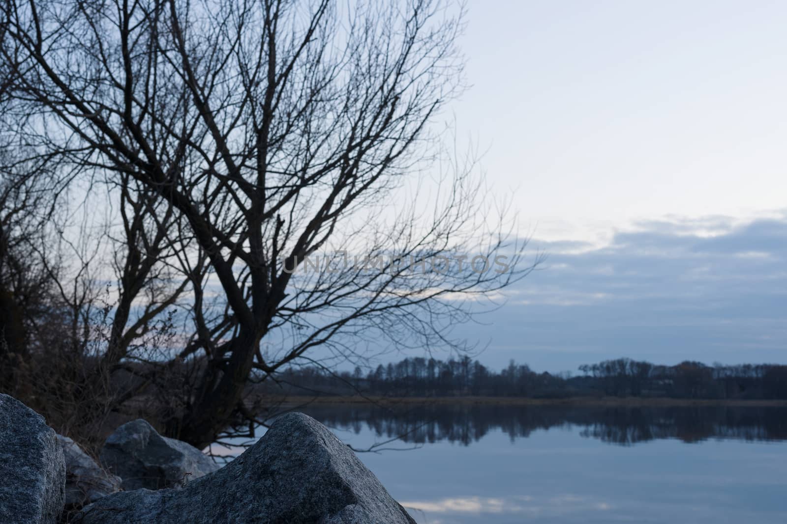 Gray evening sunset above the lake or river. Blue clouds on hori by alexsdriver