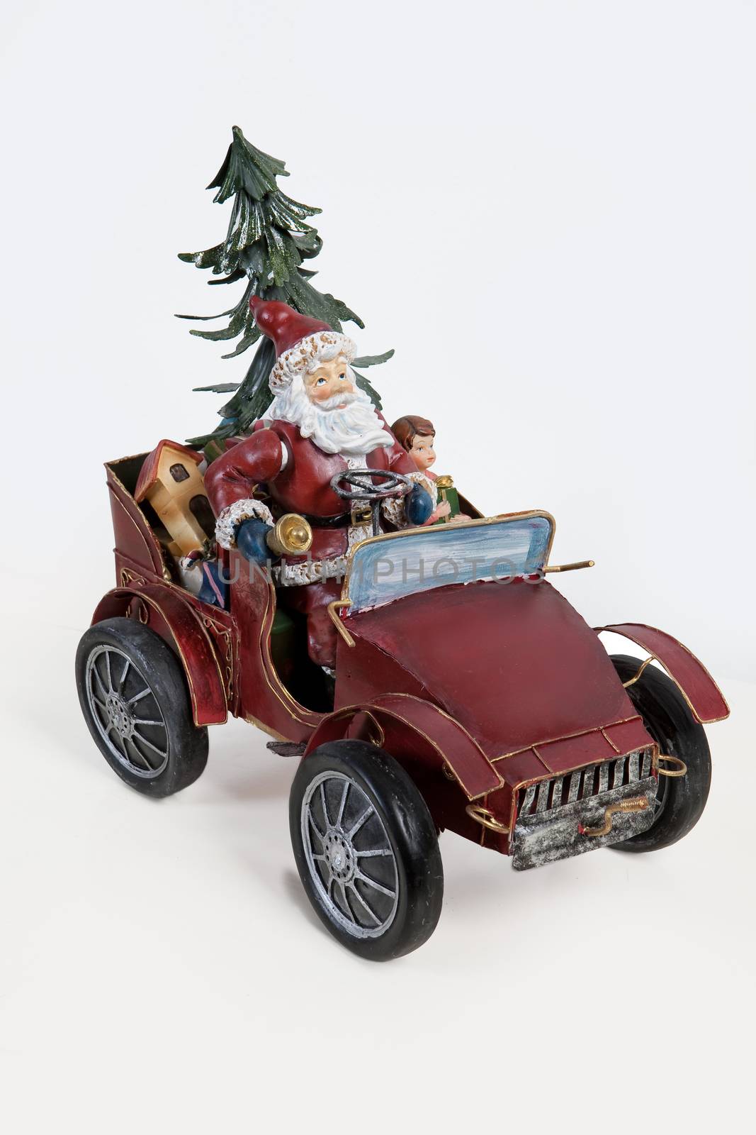Statuette of Santa Klaus sitting in an old car on isolated background