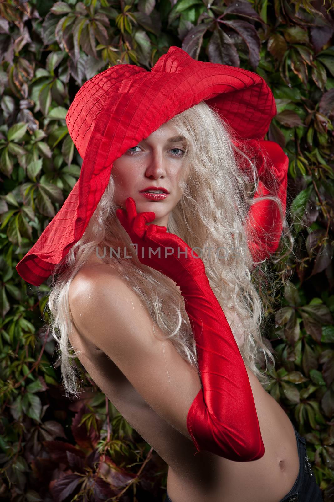 Young woman in a red hat and red long gloves in a garden