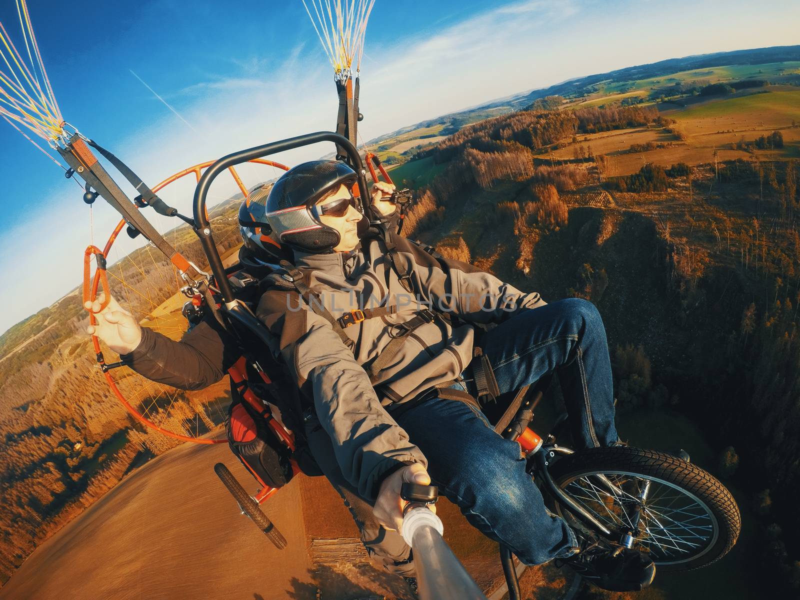 Powered paragliding tandem flight, man taking selfie with action camera