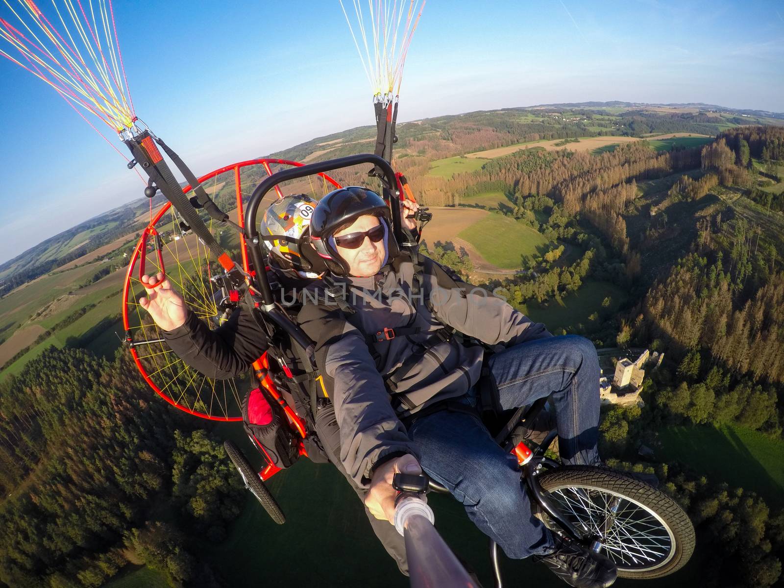 Powered paragliding tandem flight, man taking selfie with action camera