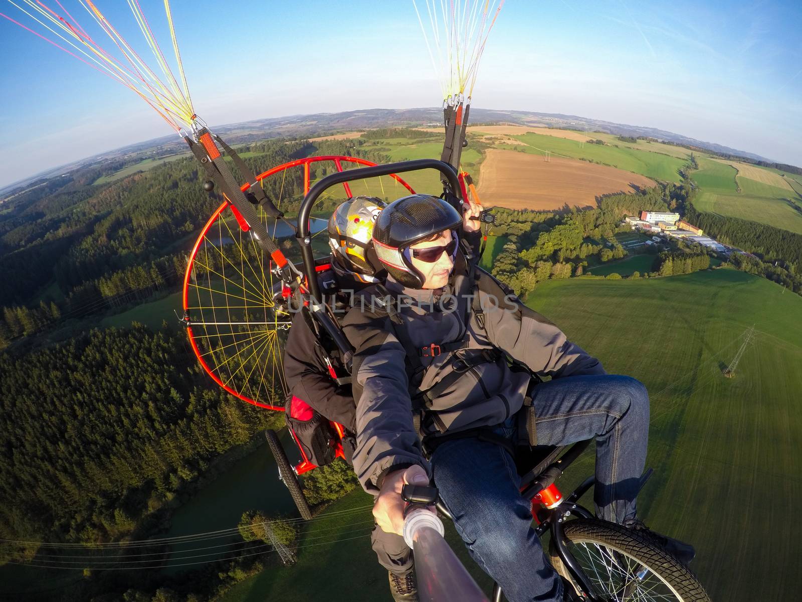 Powered paragliding tandem flight, man taking selfie with action camera