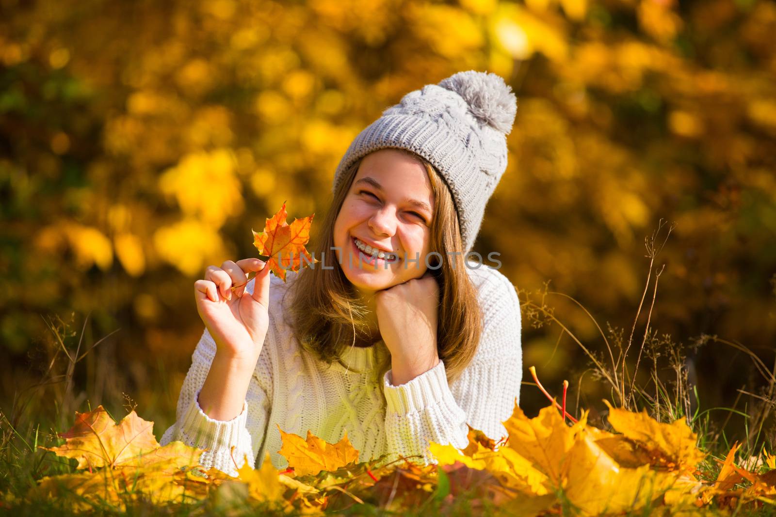 Portrait of pretty nice teenage girl with dental braces in autumn park , background with copy space for text
