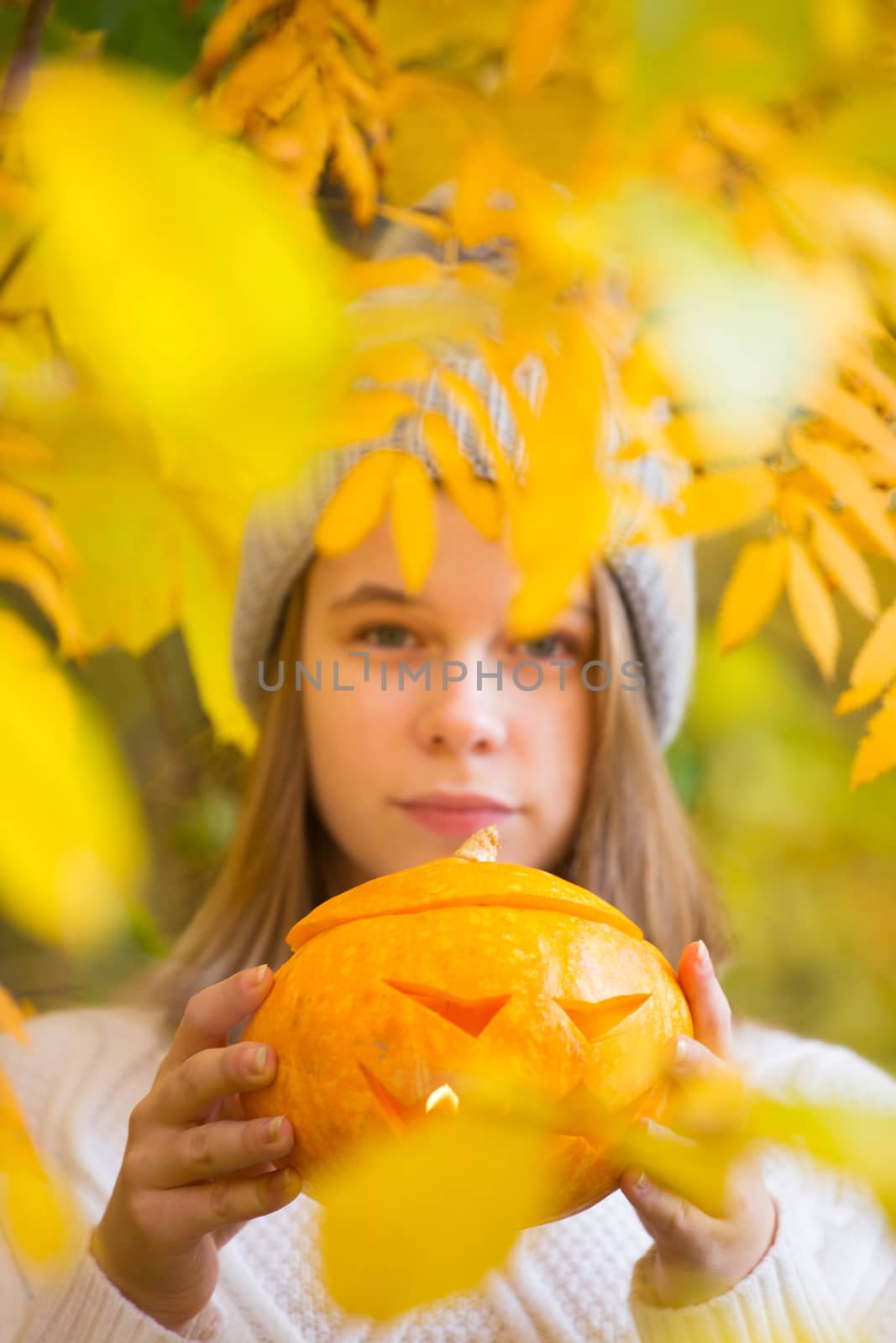 Teenage girl holding halloween pumpkin by destillat