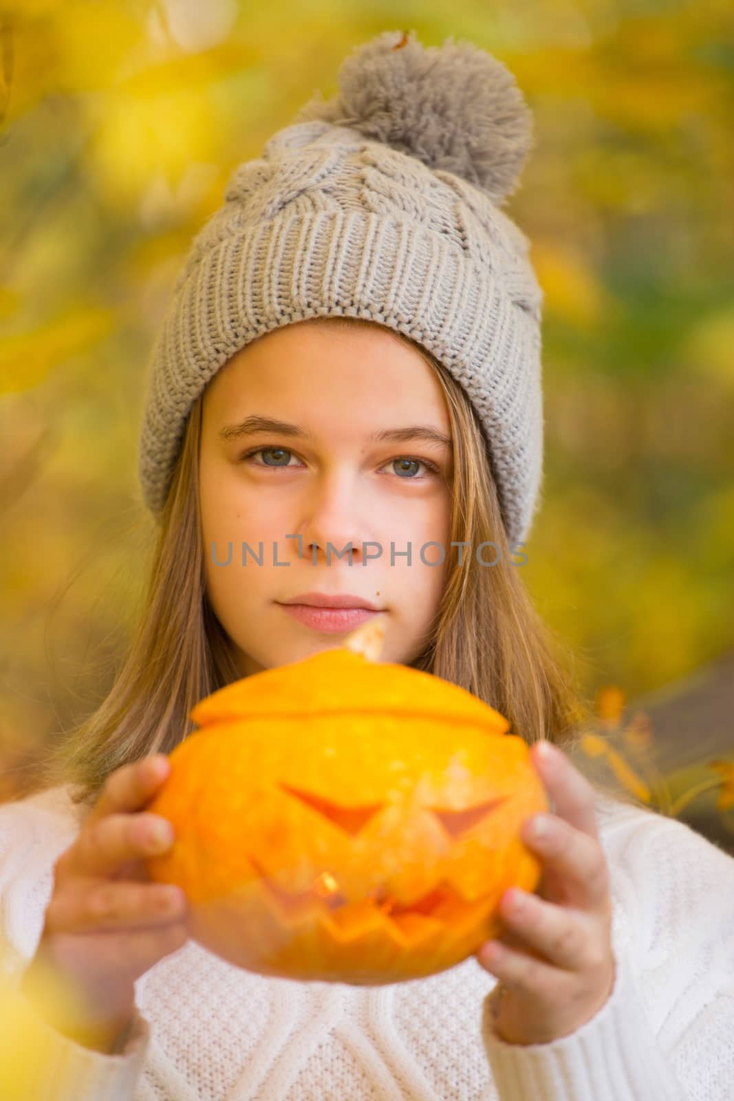 Teenage girl holding halloween pumpkin by destillat