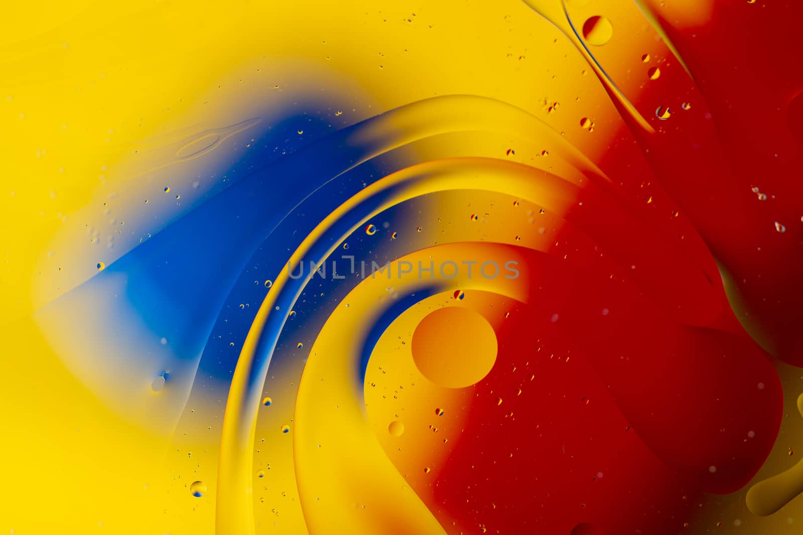 Abstract oil spots in motion on water on blurred yellow background. Red and blue spots on blurred background. Photo with small depth of field.