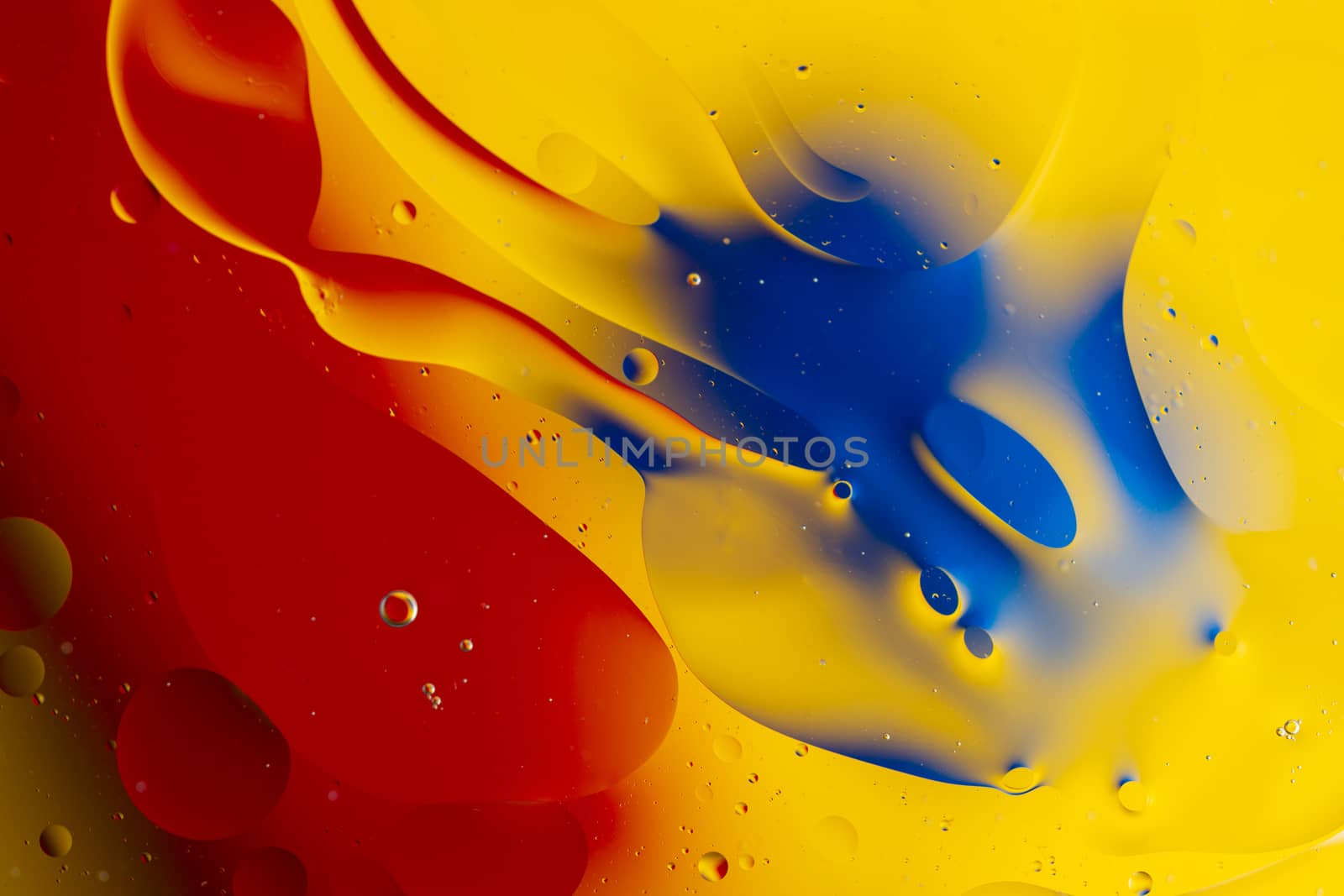 Abstract oil spots in motion on water on blurred yellow backgrou by alexsdriver