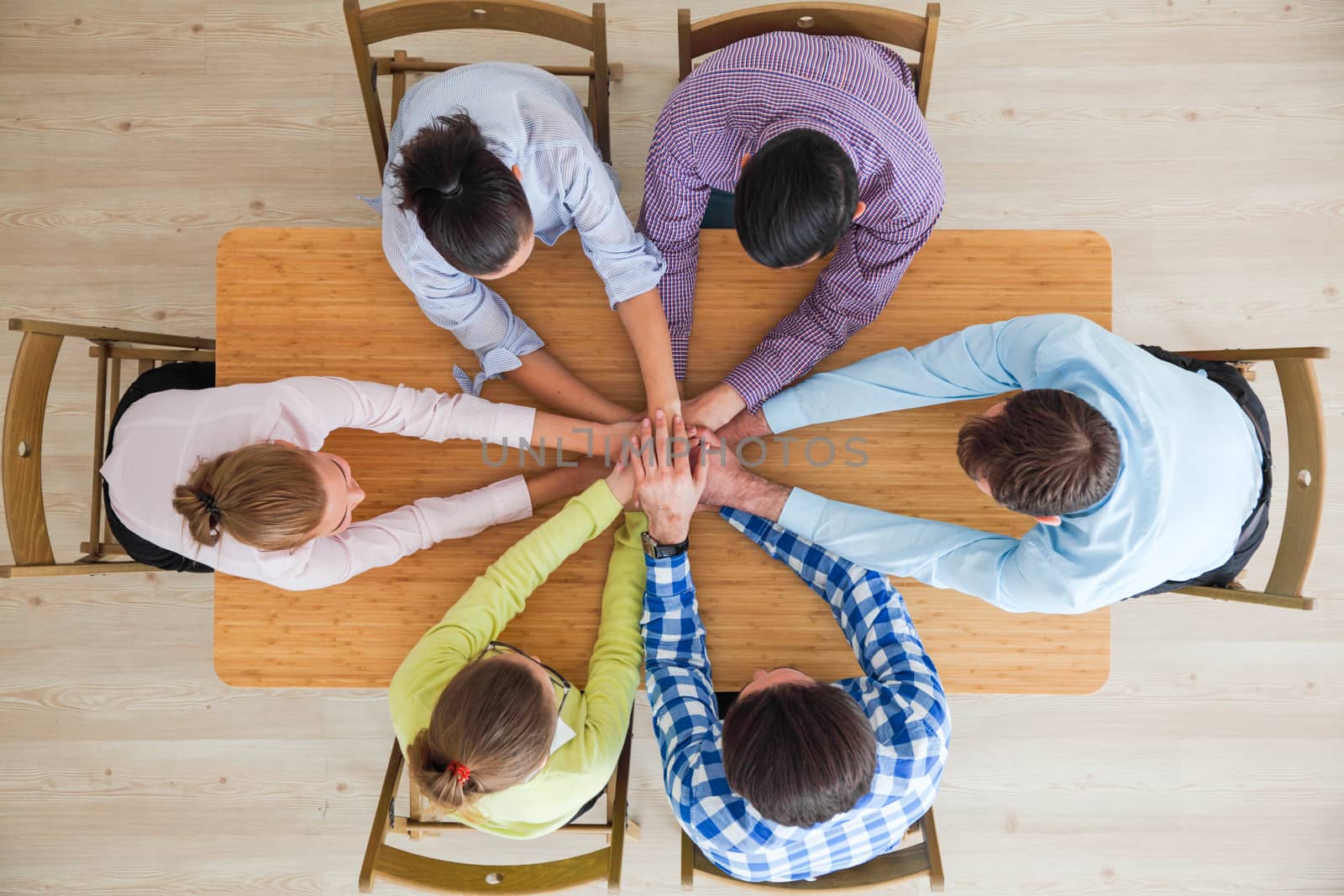 Top view of business people putting their hands on top of each other stacking at conference